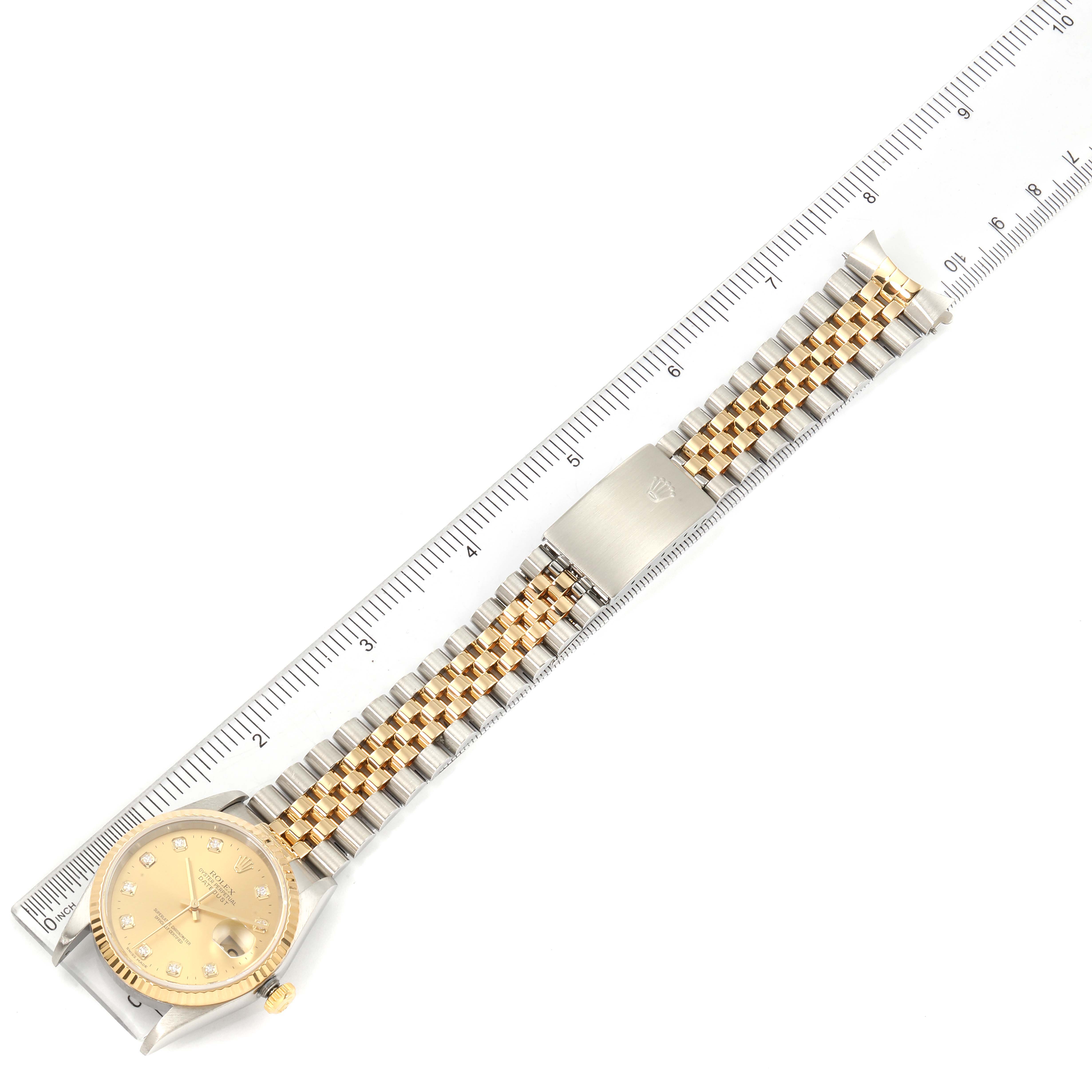 This image shows the full face and bracelet of the Rolex Datejust 16233 Men's Steel and Gold (two tone) Champagne Dial 16233 Men's Steel and Gold (two tone) Champagne Dial watch, aligned next to a ruler for scale.