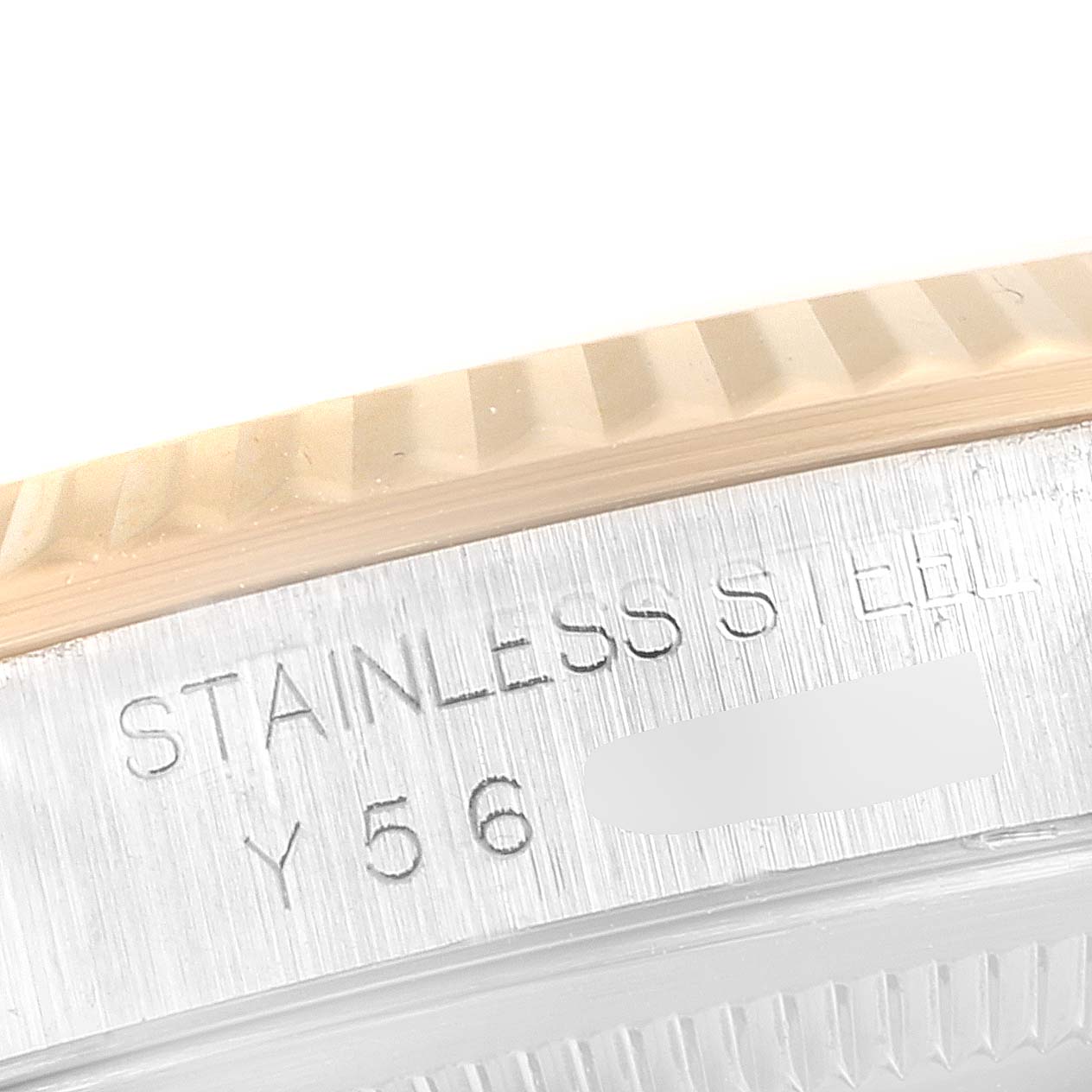 This close-up image of a Rolex Datejust 16233 Men's Steel and Gold (two tone) Champagne Dial 16233 Men's Steel and Gold (two tone) Champagne Dial watch shows the edge of the fluted bezel and part of the serial number engraved on the stainless steel case.