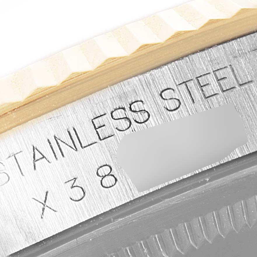 This close-up image of a Rolex Datejust 16233 Men's Steel and Gold (two tone) Champagne Dial 16233 Men's Steel and Gold (two tone) Champagne Dial model shows part of the fluted bezel and the etched "STAINLESS STEEL" inscription.