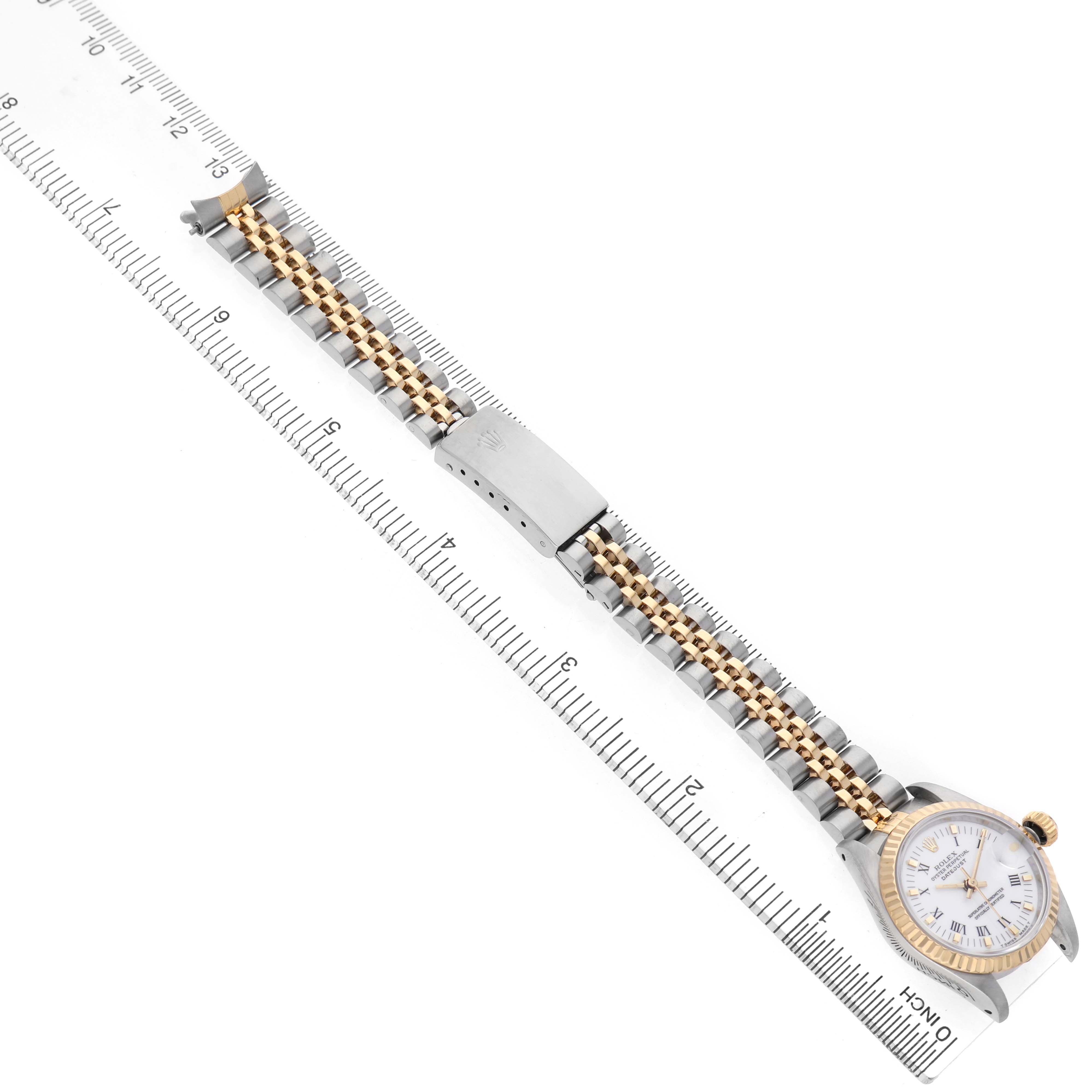 The Rolex Datejust 69173 Women's Steel and Gold (two tone) White Dial watch is shown at a slight diagonal, showcasing the bracelet and clasp alongside a ruler for scale.