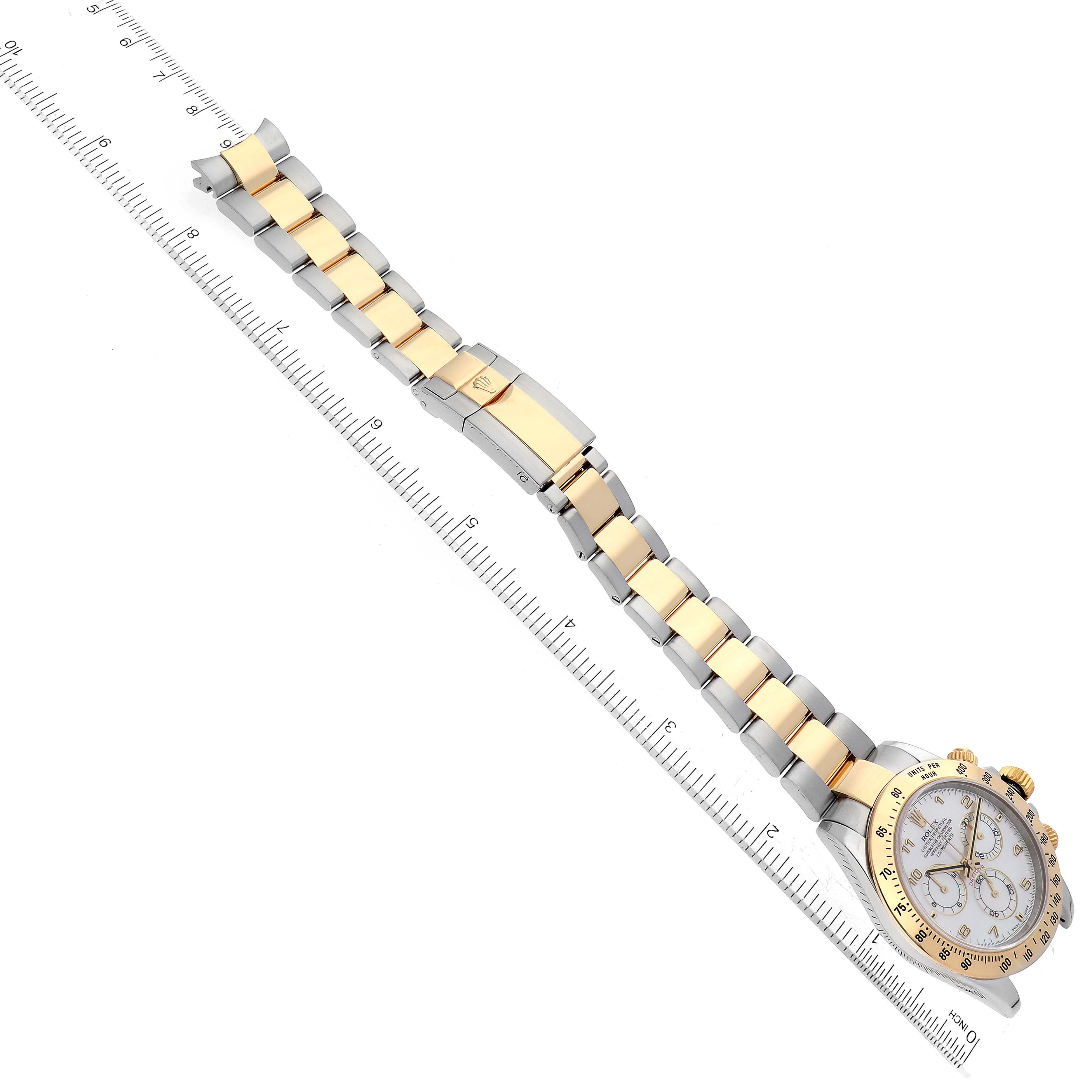 The Rolex Daytona 116523 Men's Steel and Gold (two tone) Mother of Pearl Dial 116523 Men's Steel and Gold (two tone) Mother of Pearl Dial watch is shown at an angled top-down view, displaying its face and two-tone bracelet next to a ruler.