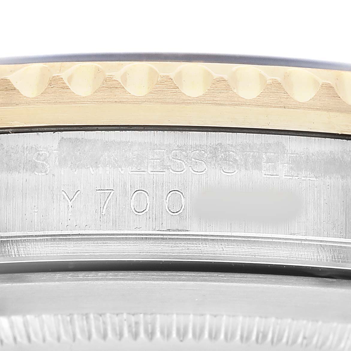 The image shows a close-up side view of the Rolex GMT-Master 16713 Men's Steel and Gold (two tone) Black Dial's case, bezel, and serial number engraving.