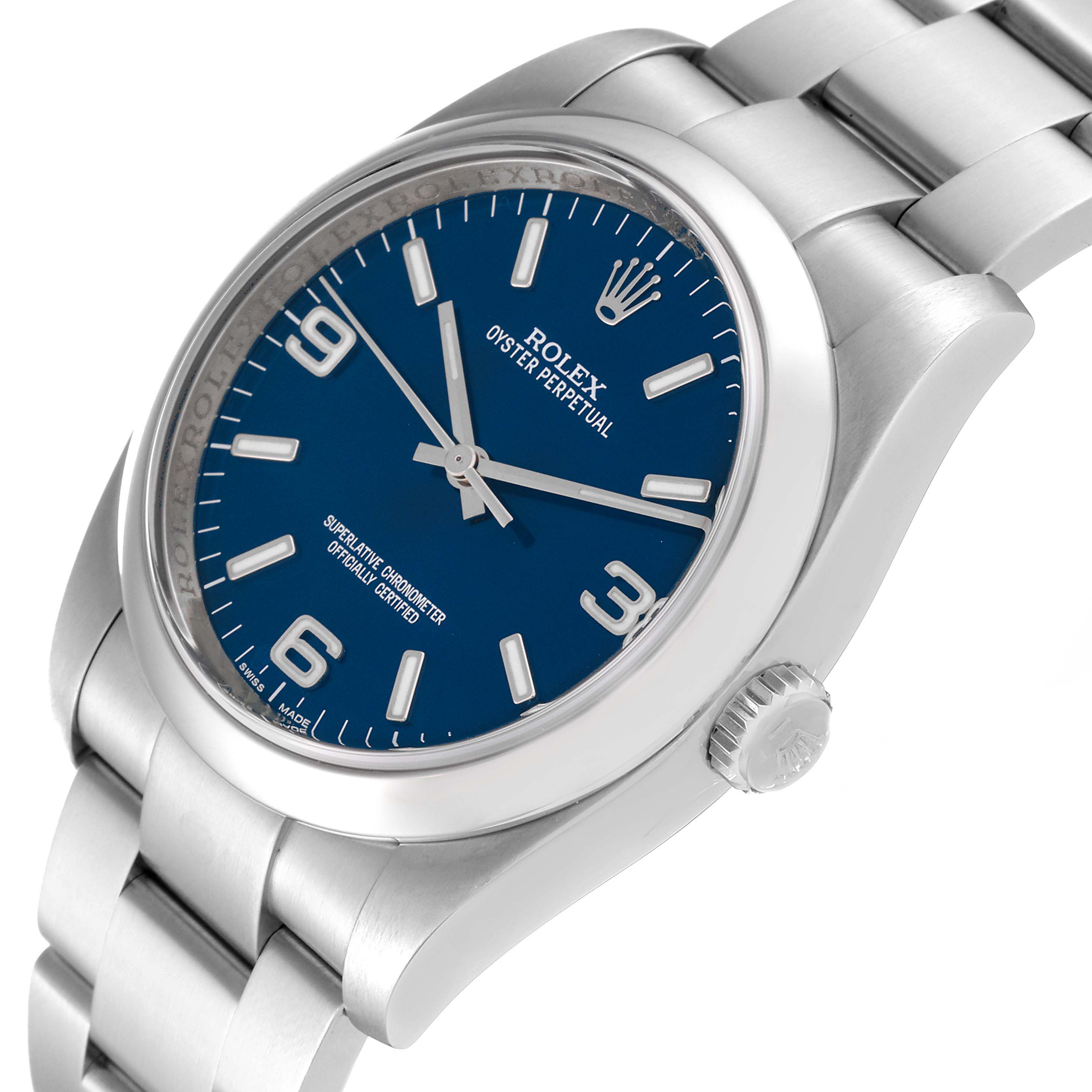 The image shows a side angle of the Rolex Oyster Perpetual 116000 Men
s Stainless Steel Blue Dial 116000 Men
s Stainless Steel Blue Dial watch, highlighting the blue dial, crown, and part of the bracelet.