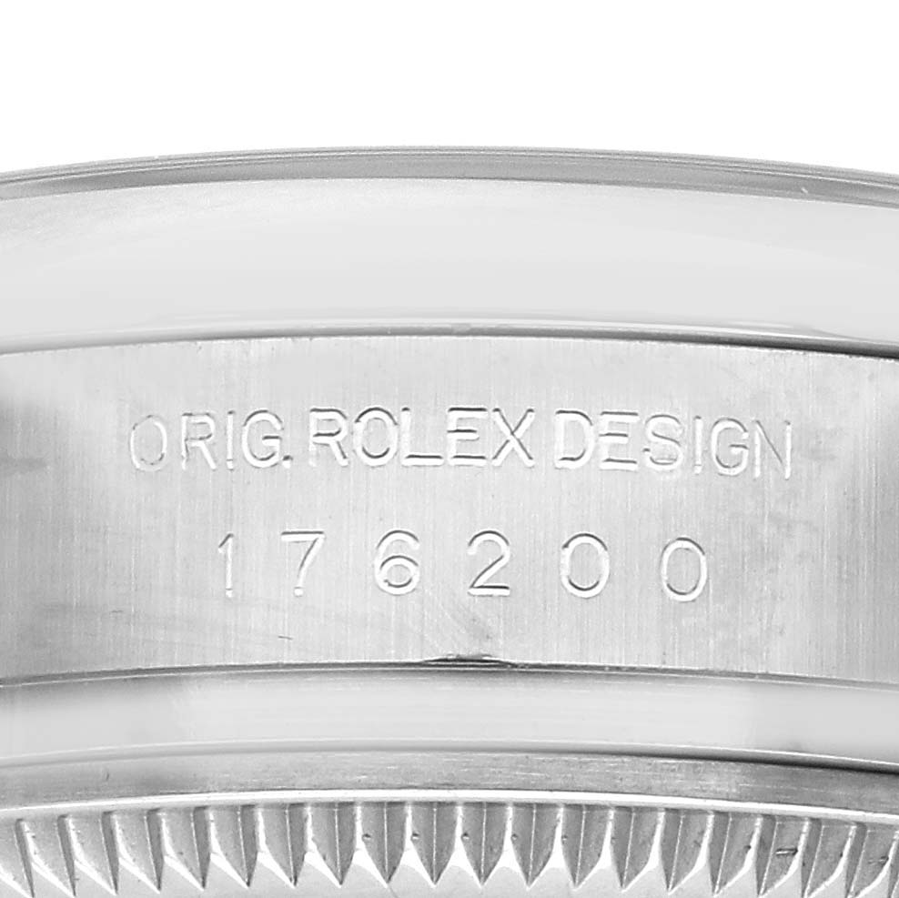 The image shows the side view of a Rolex Oyster Perpetual 176200 Women's Stainless Steel Pink Dial 176200 Women's Stainless Steel Pink Dial watch's bezel with engravings of "ORIG. ROLEX DESIGN" and a model number.