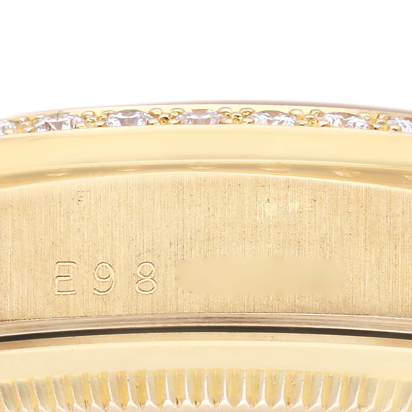 This close-up image of a Rolex President 18348 Men
s Yellow Gold Champagne Dial 18348 Men
s Yellow Gold Champagne Dial watch shows part of the bezel and a serial number engraving.