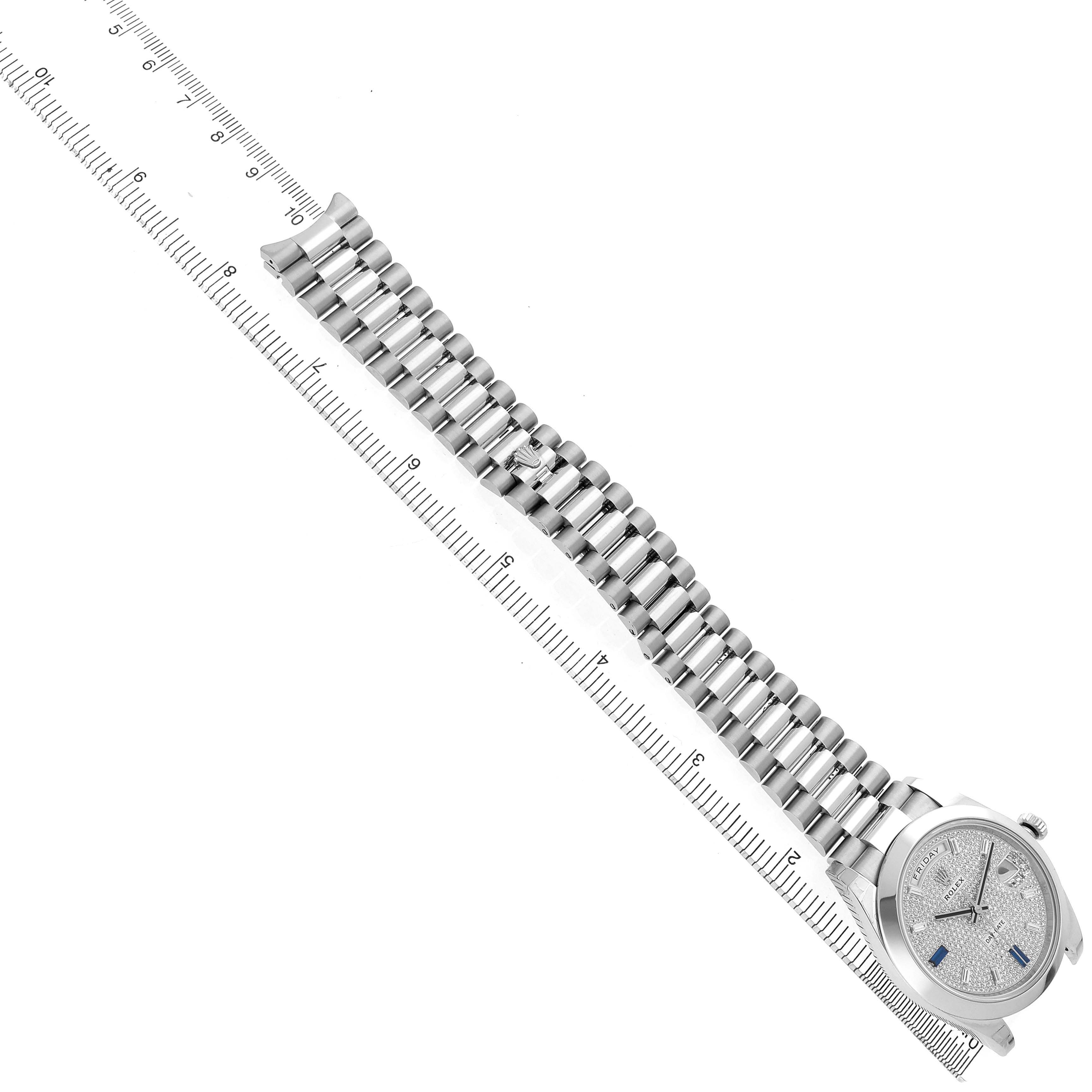 The Rolex President 228206 Men's Platinum Silver Dial watch is shown laid flat with its bracelet and partially visible face, angled along a ruler.