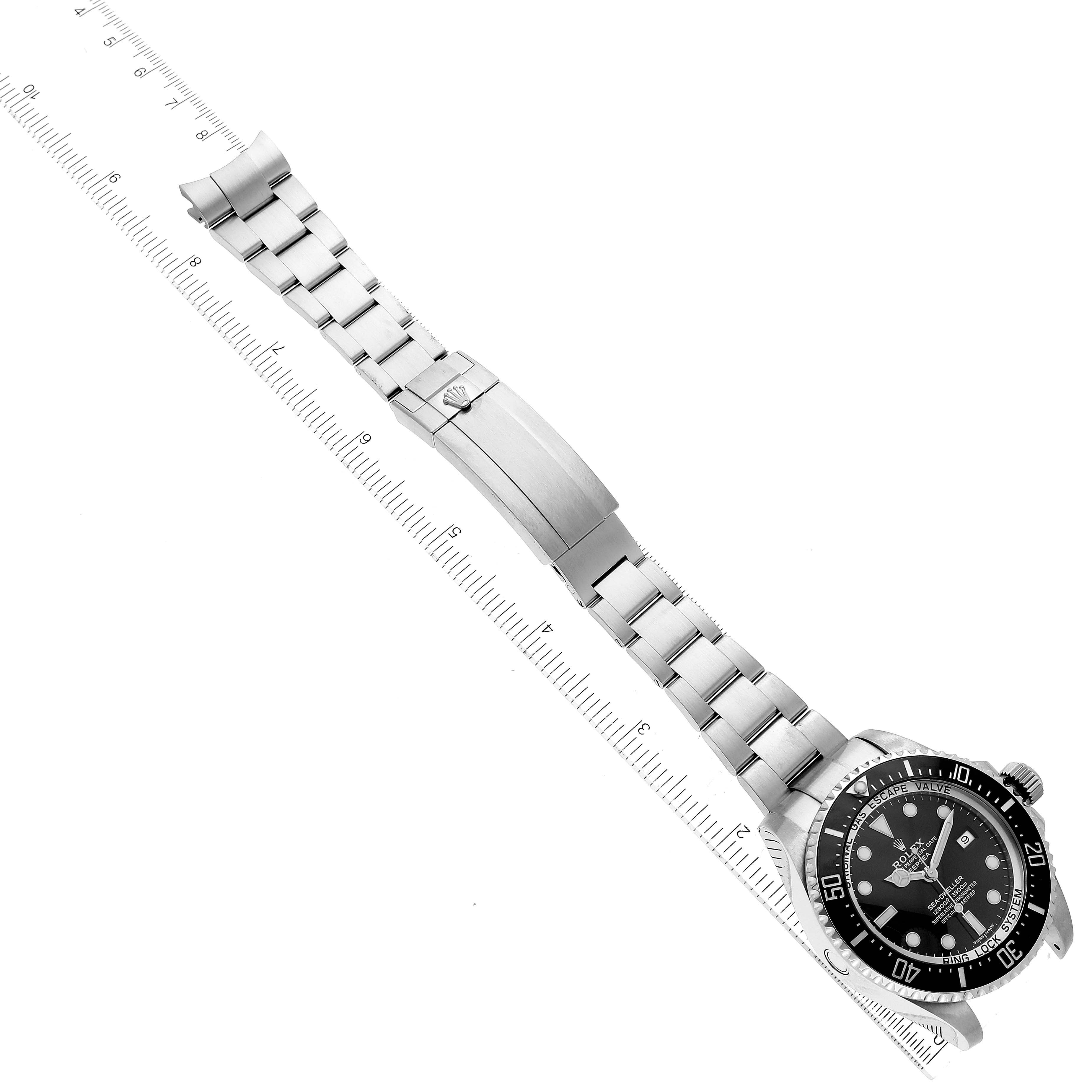 The image shows a top-down view of a Rolex Sea-Dweller 116660 Men
s Stainless Steel Black Dial 116660 Men
s Stainless Steel Black Dial watch, featuring its dial, bezel, bracelet, and clasp, aligned next to a ruler.