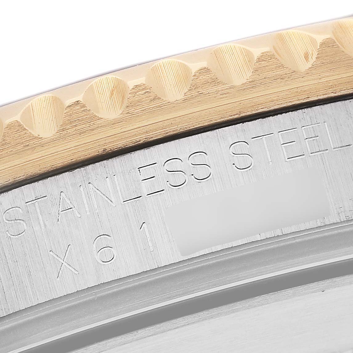 This close-up shows the side of a Rolex Submariner 16613 Men's Steel and Gold (two tone) Blue Dial 16613 Men's Steel and Gold (two tone) Blue Dial's bezel and part of its stainless steel case back with engraved text.