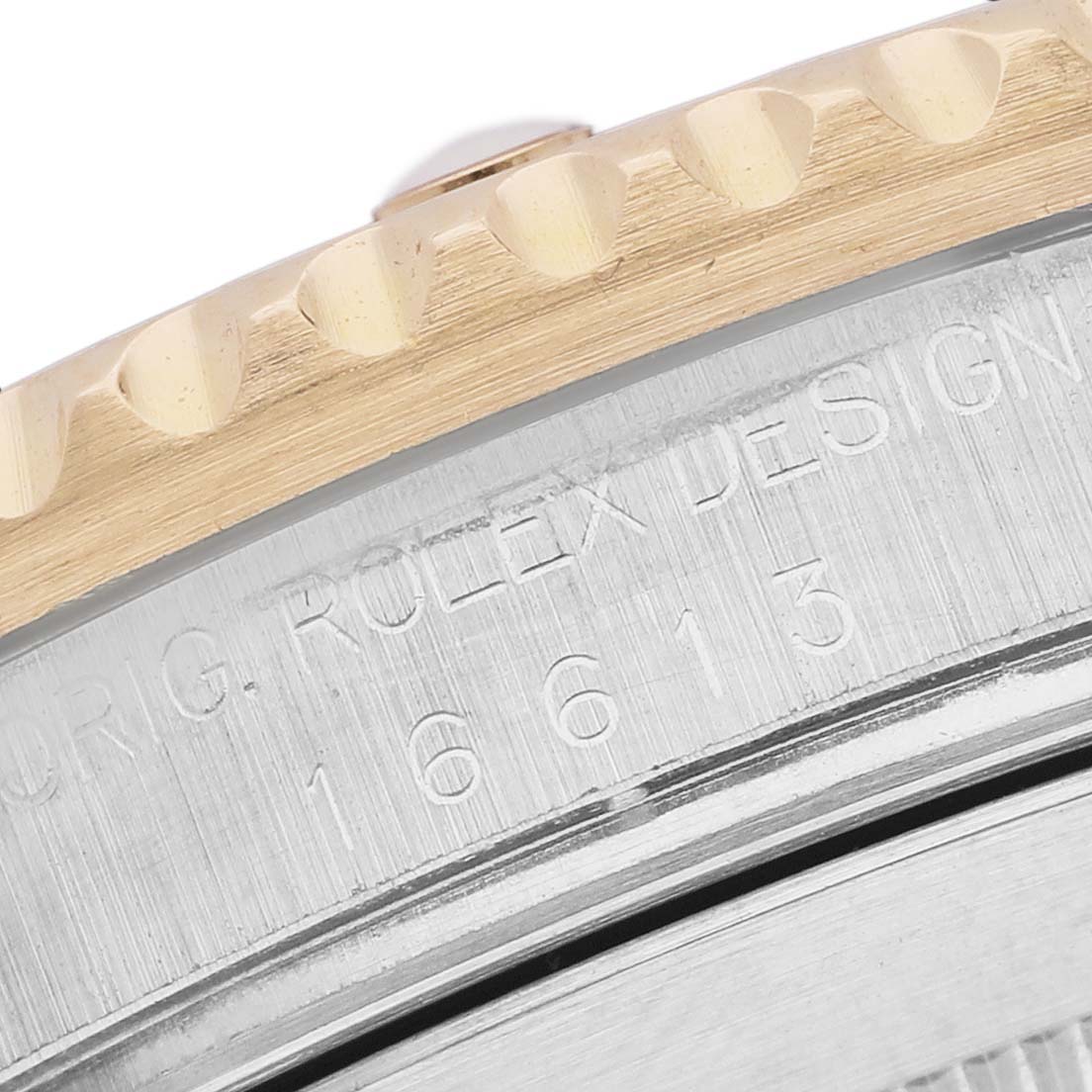 The image shows a close-up of the case edge and bezel of a Rolex Submariner 16613 Men's Steel and Gold (two tone) Black Dial watch, featuring engraving and detailing.