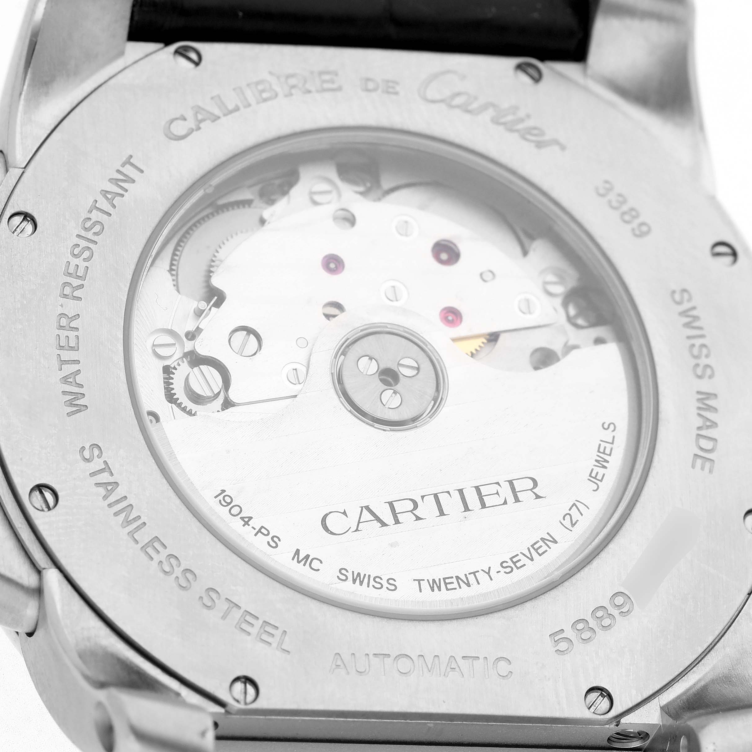 The image shows the back of a Calibre de Cartier watch, revealing the mechanical movement and inscriptions.