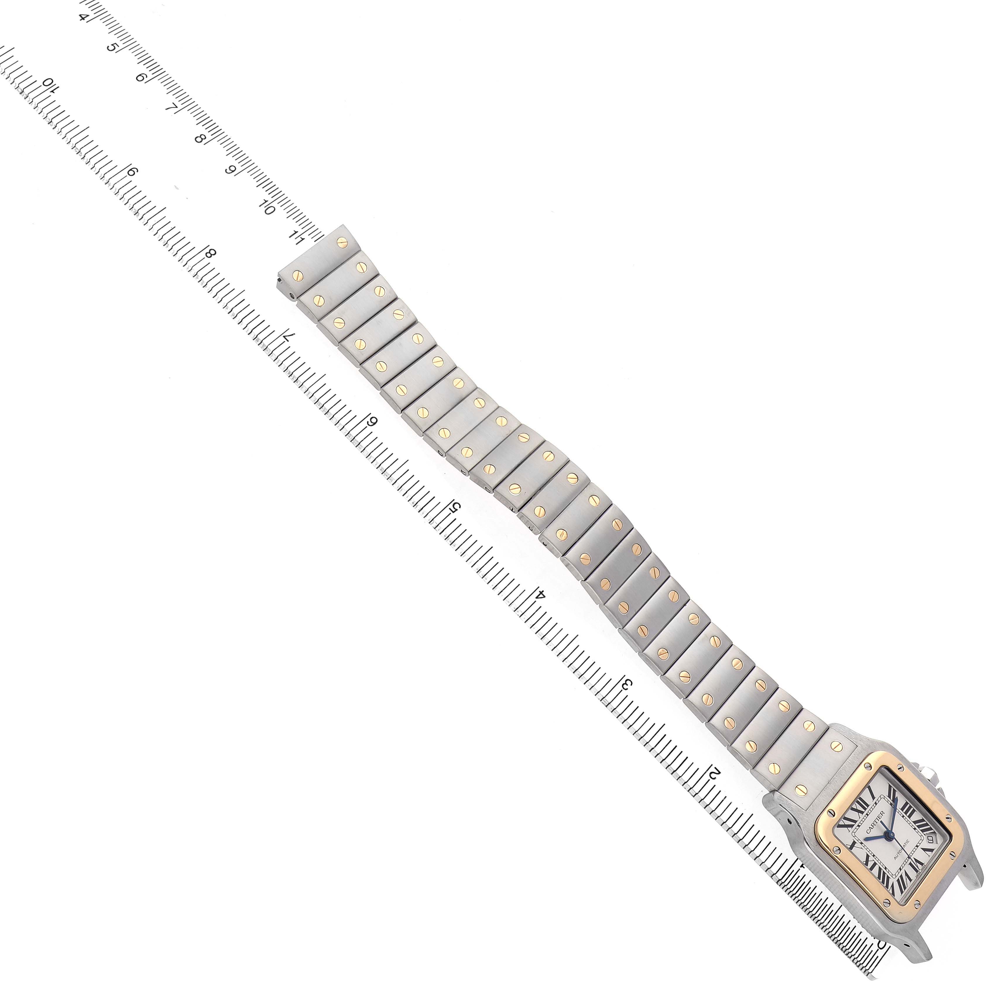 The image shows a Cartier Santos W20099C4 Men's Steel and Gold (two tone) Silver Dial watch from a top-down angle, highlighting the bracelet and face alongside a ruler for scale.