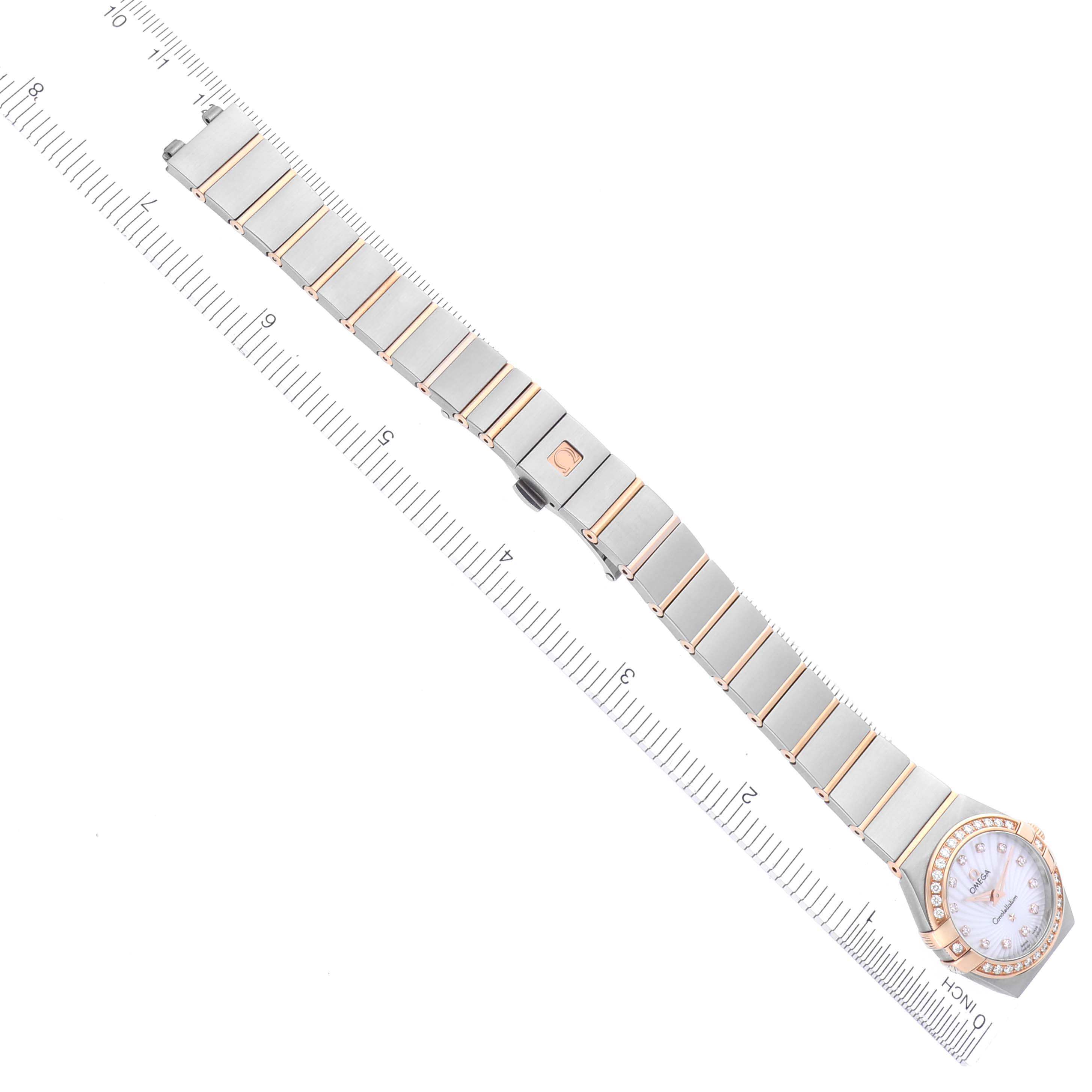 The image shows the Omega 123.25.24.60.55.002 Women's Steel and Gold (two tone) Mother of Pearl Dial 123.25.24.60.55.002 Women's Steel and Gold (two tone) Mother of Pearl Dial Constellation Steel Rose Gold Diamond Watch 123.25.24.60.55.002 laid flat alongside a ruler, highlighting the bracelet and case.