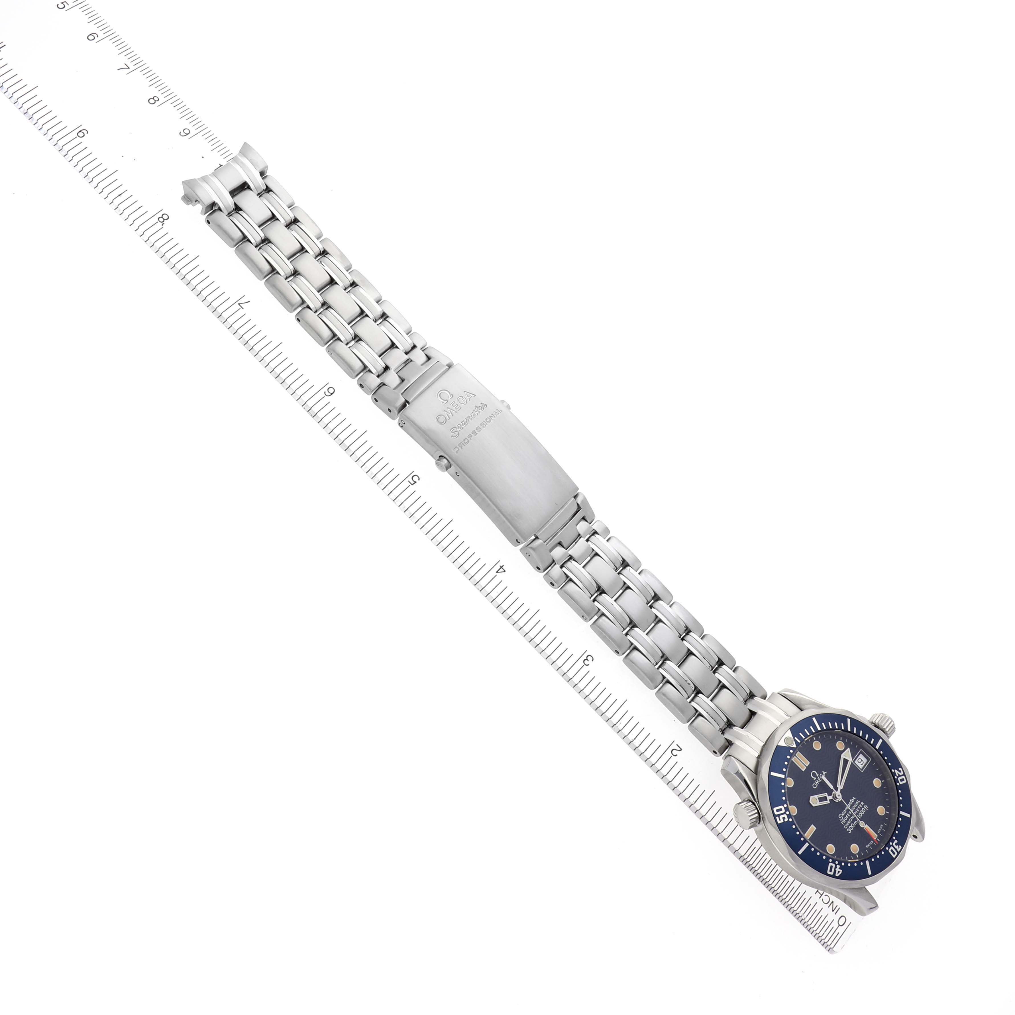 The image shows an Omega Seamaster 2551.80.00 Men
s Stainless Steel Blue Dial 2551.80.00 Men
s Stainless Steel Blue Dial watch from a top view, displaying the face, bracelet, and clasp laid alongside a ruler.