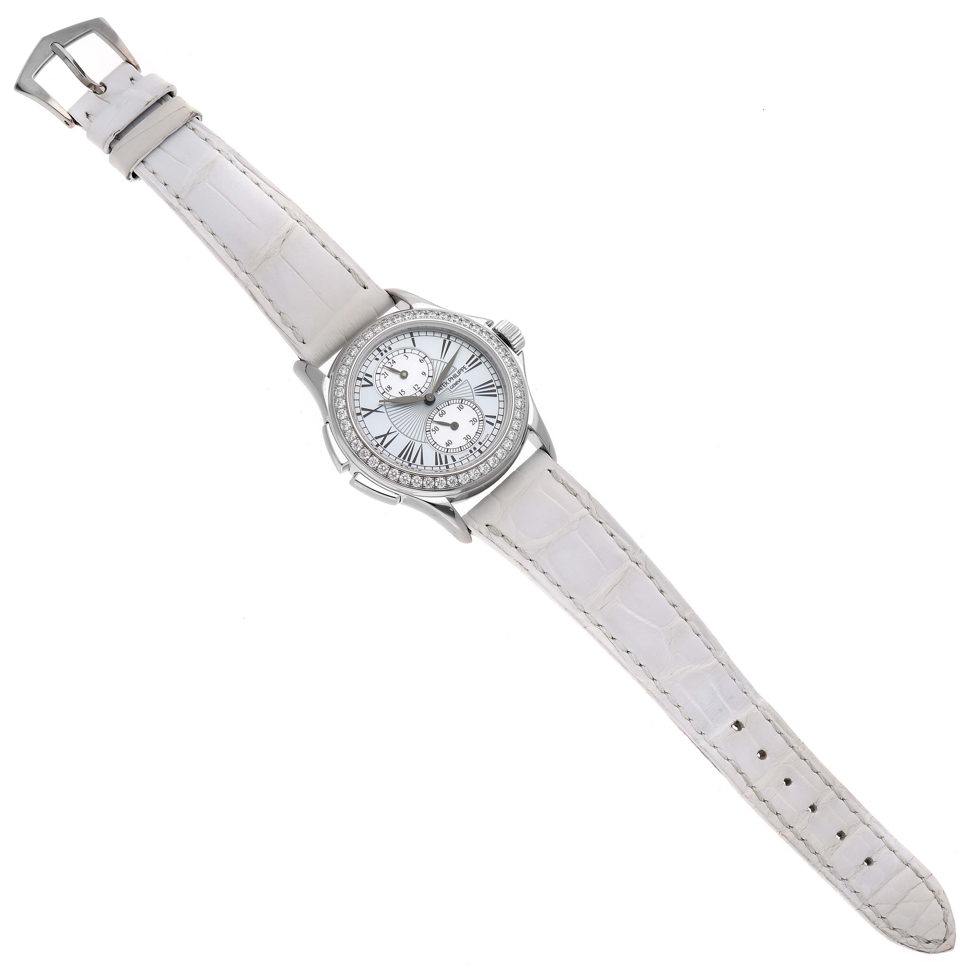 The image shows a top view of a Patek Philippe Calatrava 4934G-001 Women's White Gold Mother of Pearl Dial 4934G-001 Women's White Gold Mother of Pearl Dial watch featuring a white strap and diamond-studded bezel.