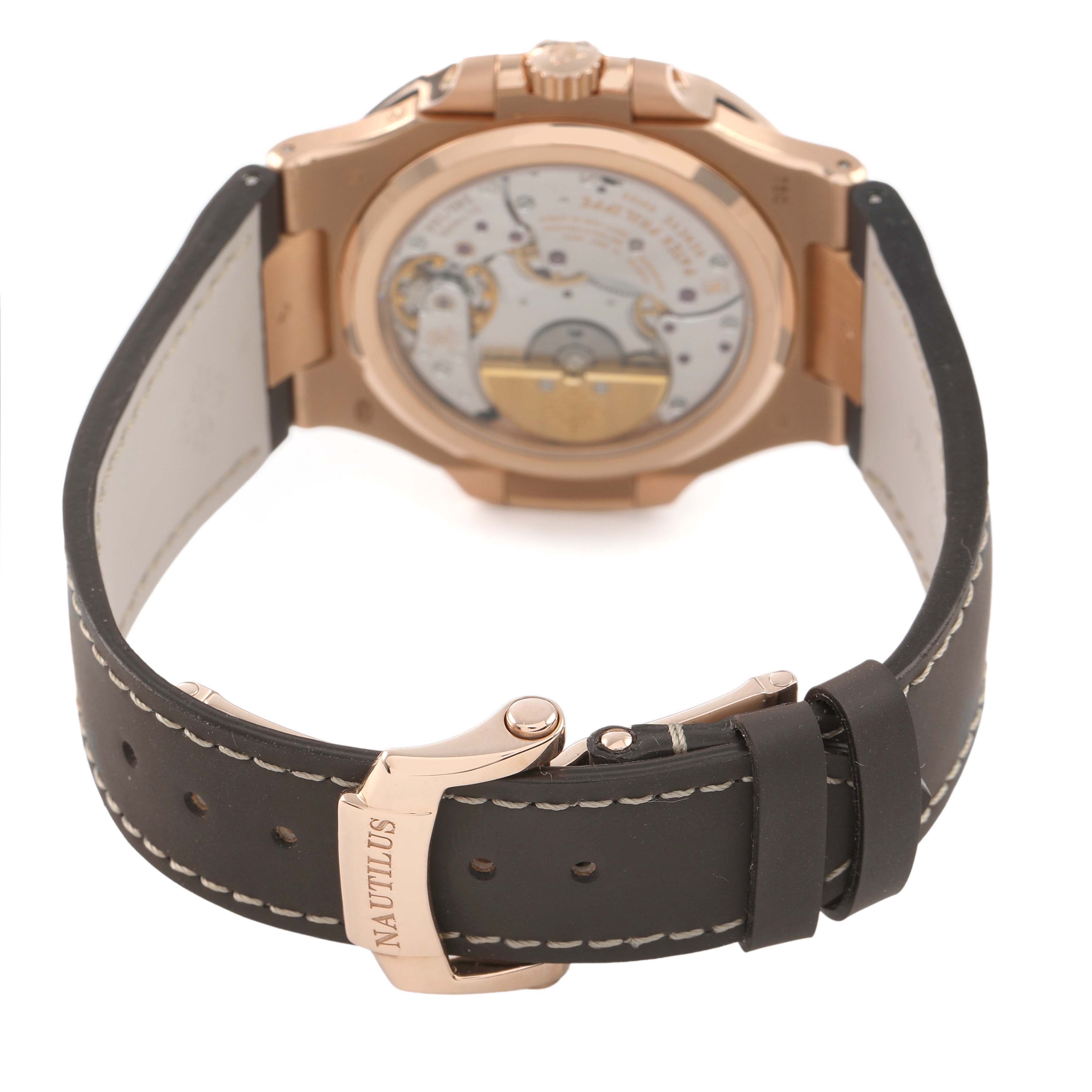 The image shows the back view of a Patek Philippe Nautilus 5712R-001 Men's Rose Gold Brown Dial watch, highlighting its movement and clasp on the strap.