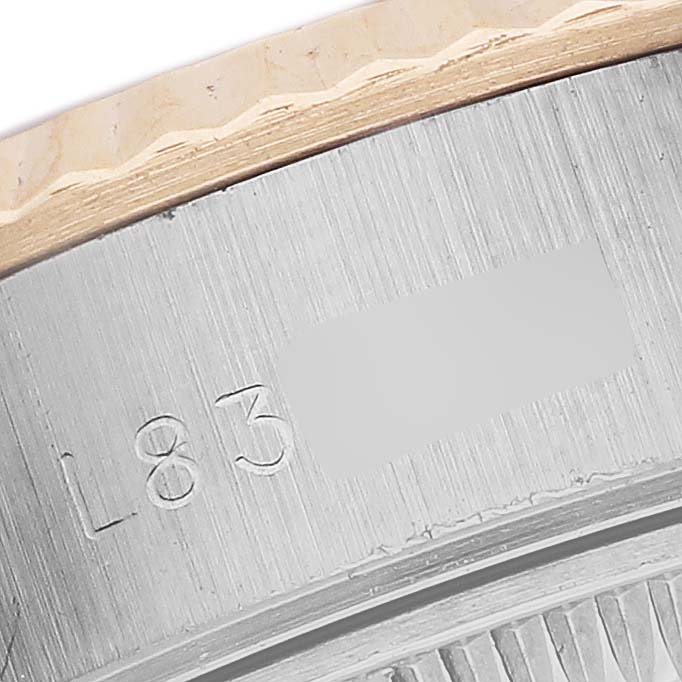 The image shows a close-up of the side and edge of a Rolex Datejust 69173 Women's Steel and Gold (two tone) Champagne Dial's bezel and case, with partial engravings visible.