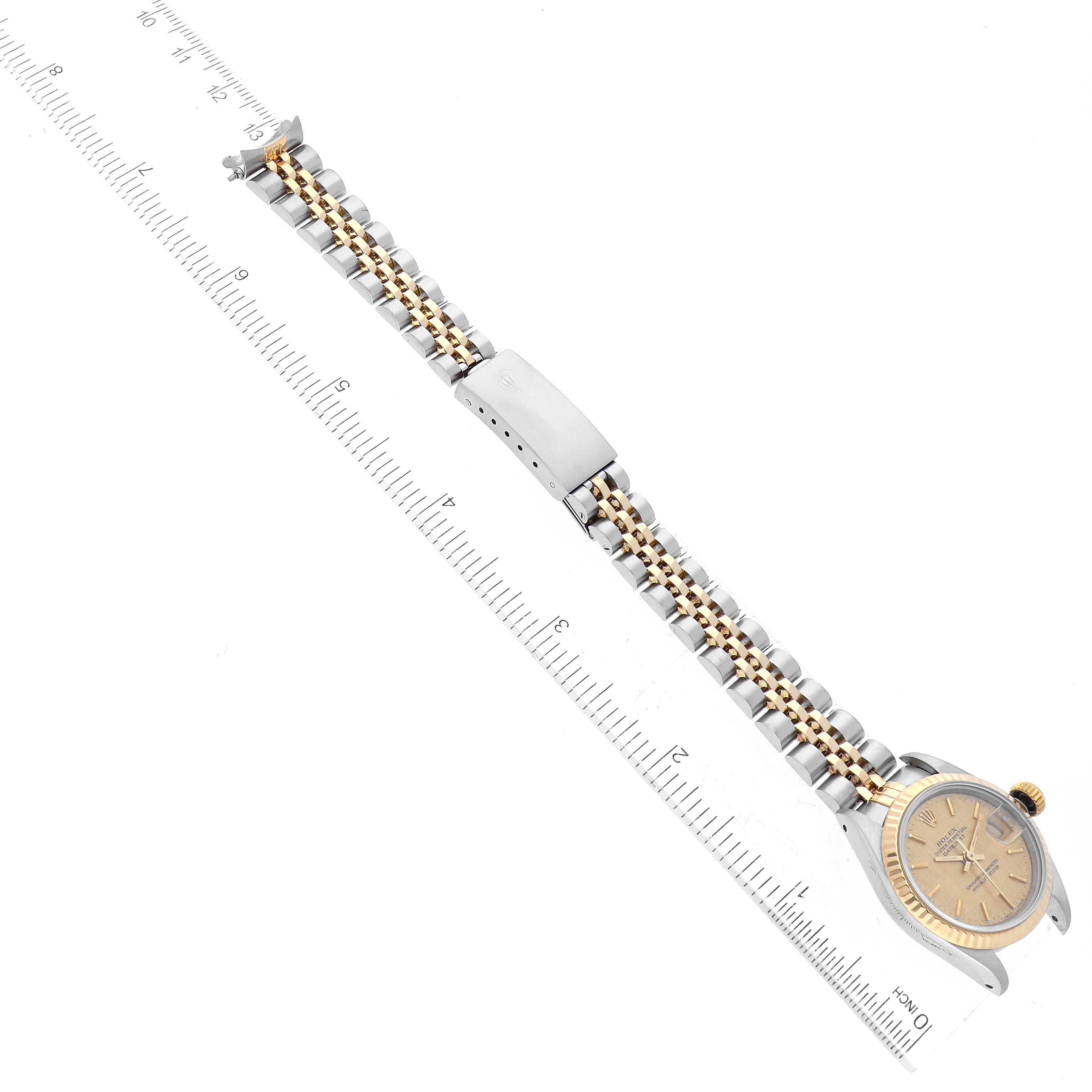 The image shows a Datejust model Rolex watch laid flat with a ruler measuring its length, including the watch face and the bracelet.