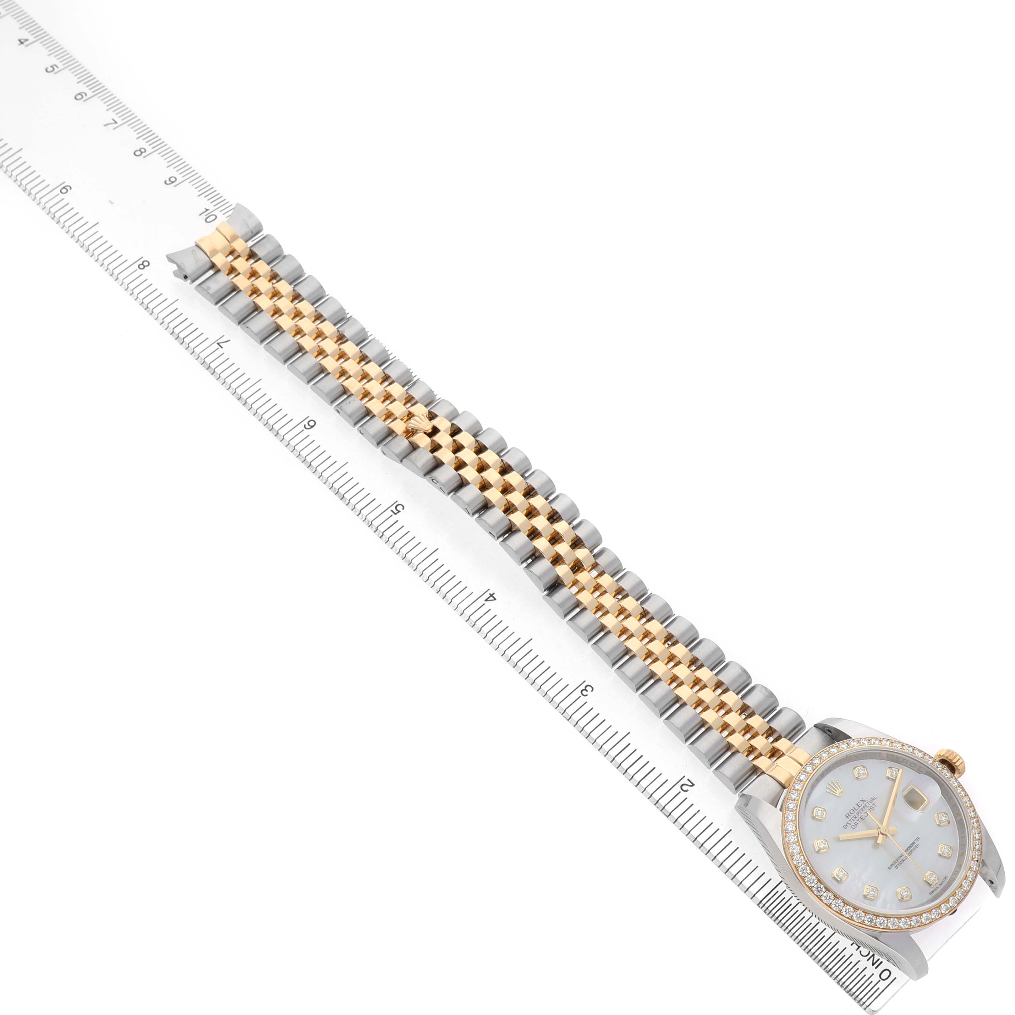 The Rolex Datejust 116243 Men's Steel and Gold (two tone) Mother of Pearl Dial watch is shown from a top view, displaying the face and two-tone bracelet alongside a ruler for scale.
