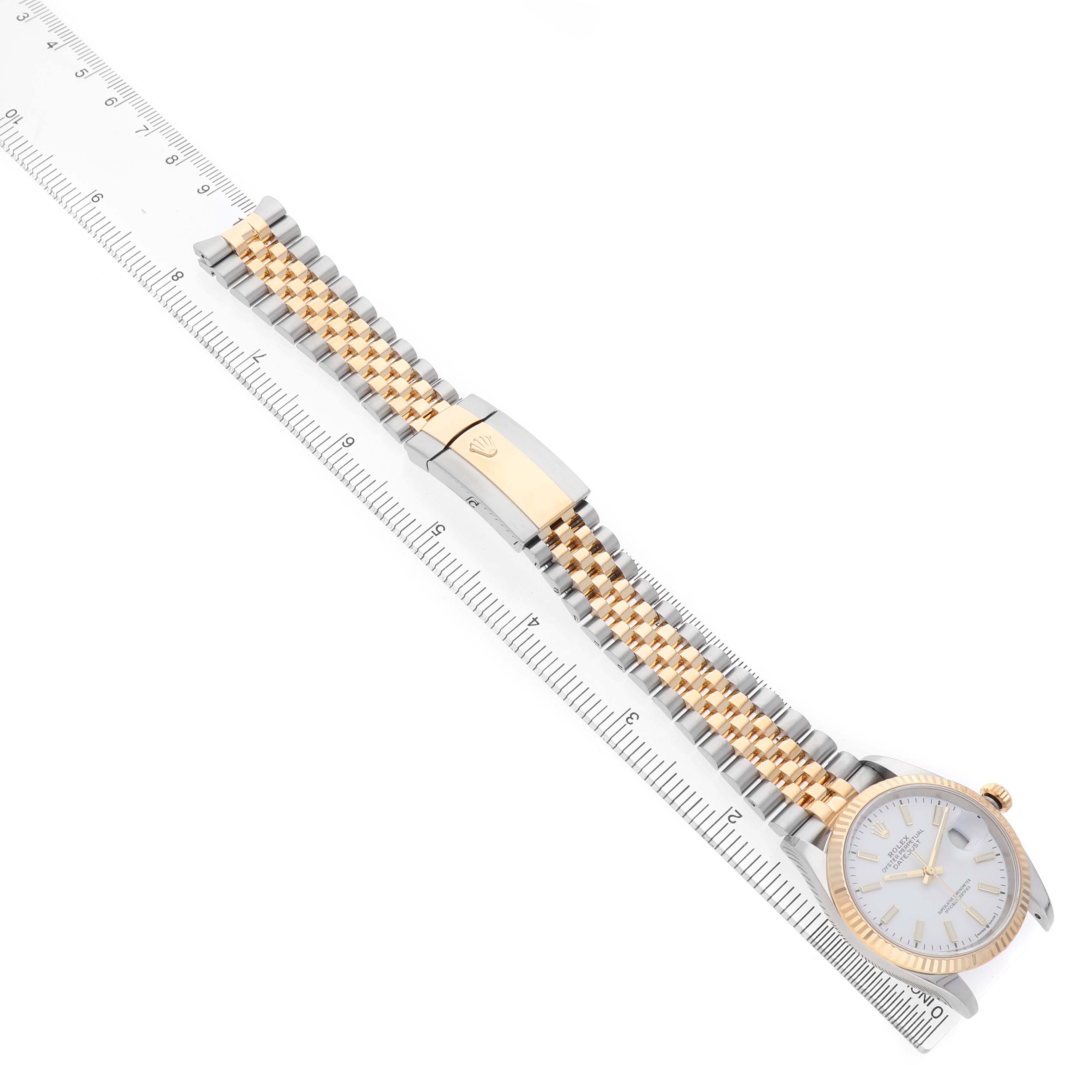 The Rolex Datejust 126233 Men's Steel and Gold (two tone) White Dial watch is shown from a top angle, highlighting the band, clasp, and partial face alongside a ruler.