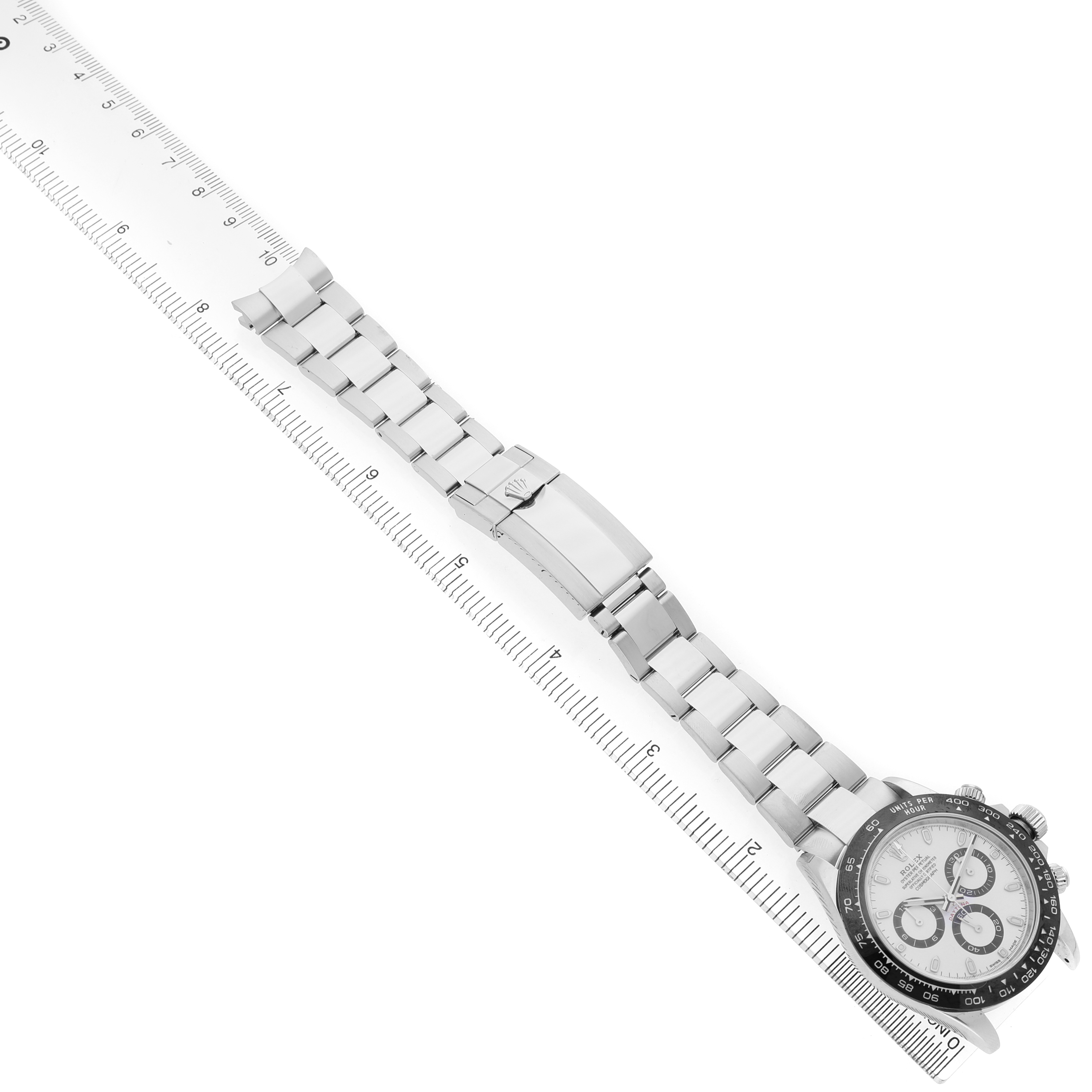 The Rolex Daytona 116500LN Men's Stainless Steel White Dial is displayed diagonally with a focus on the full bracelet and clasp, alongside a ruler for scale.