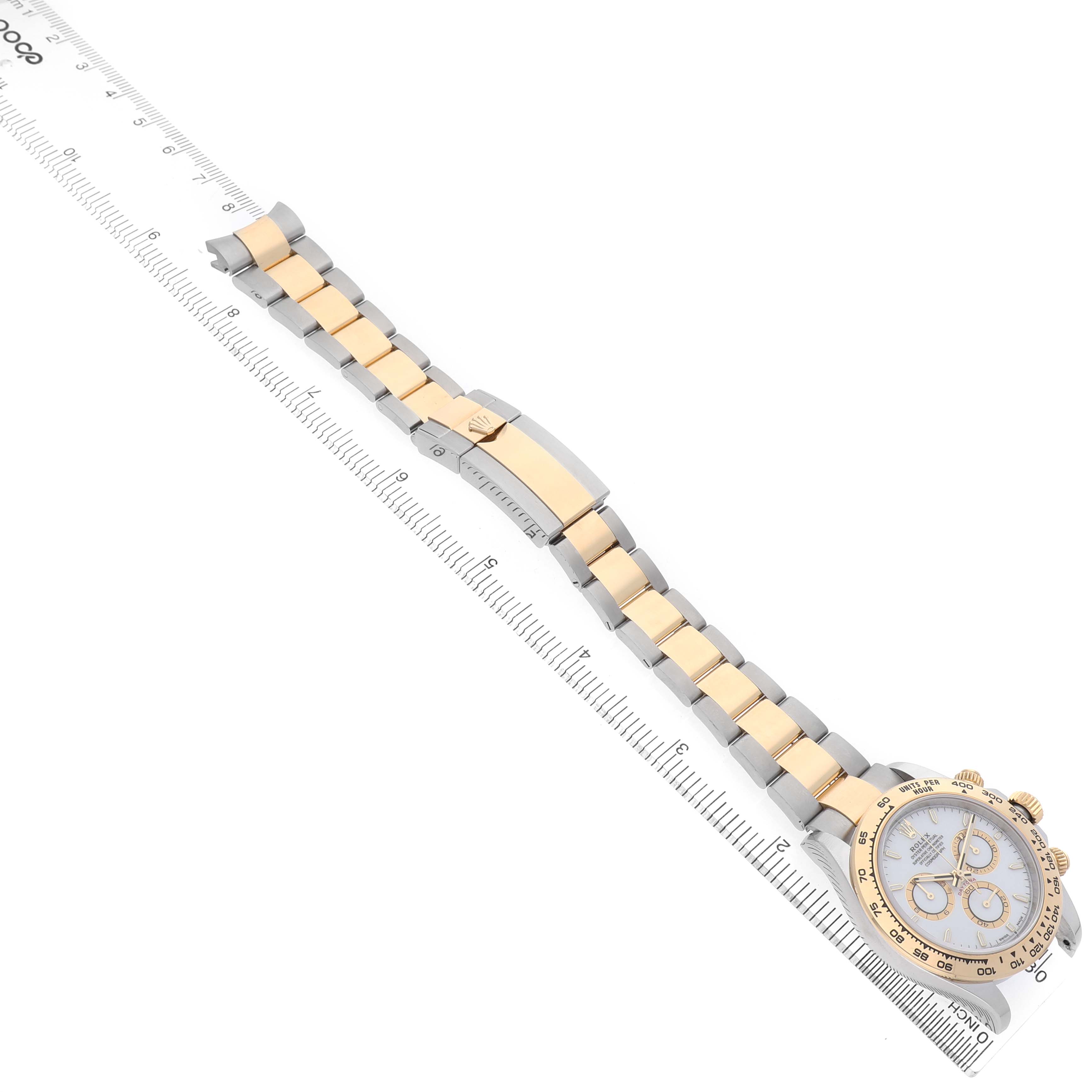The Rolex Daytona 126503 Men's Steel and Gold (two tone) White Dial watch is shown at a diagonal angle with focus on the bracelet and clasp alongside a ruler for scale.