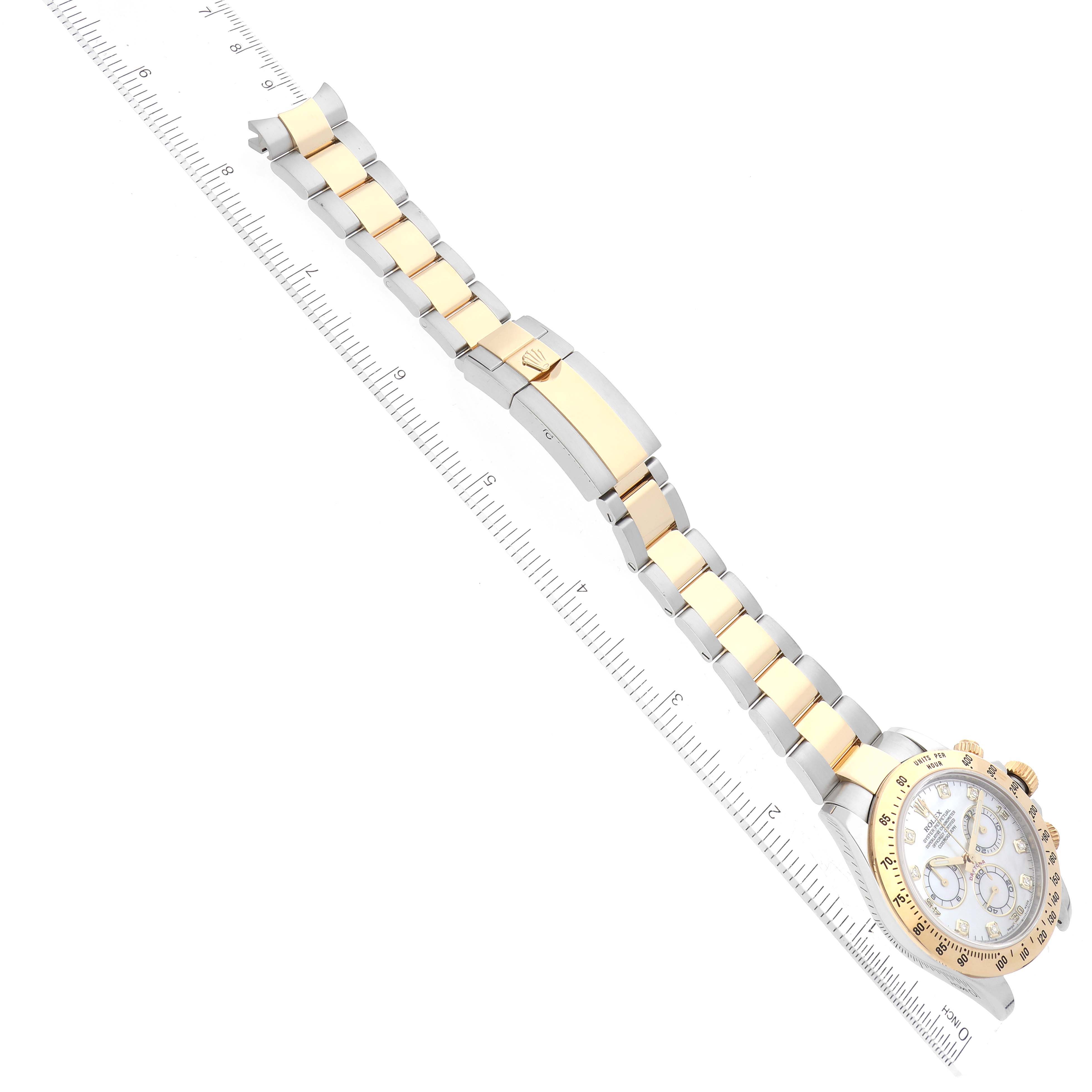 The image shows a Rolex Daytona 116523NG Men's Steel and Gold (two tone) Mother of Pearl Dial 116523NG Men's Steel and Gold (two tone) Mother of Pearl Dial watch at an angle displaying the face, gold bezel, and two-tone bracelet next to a ruler.