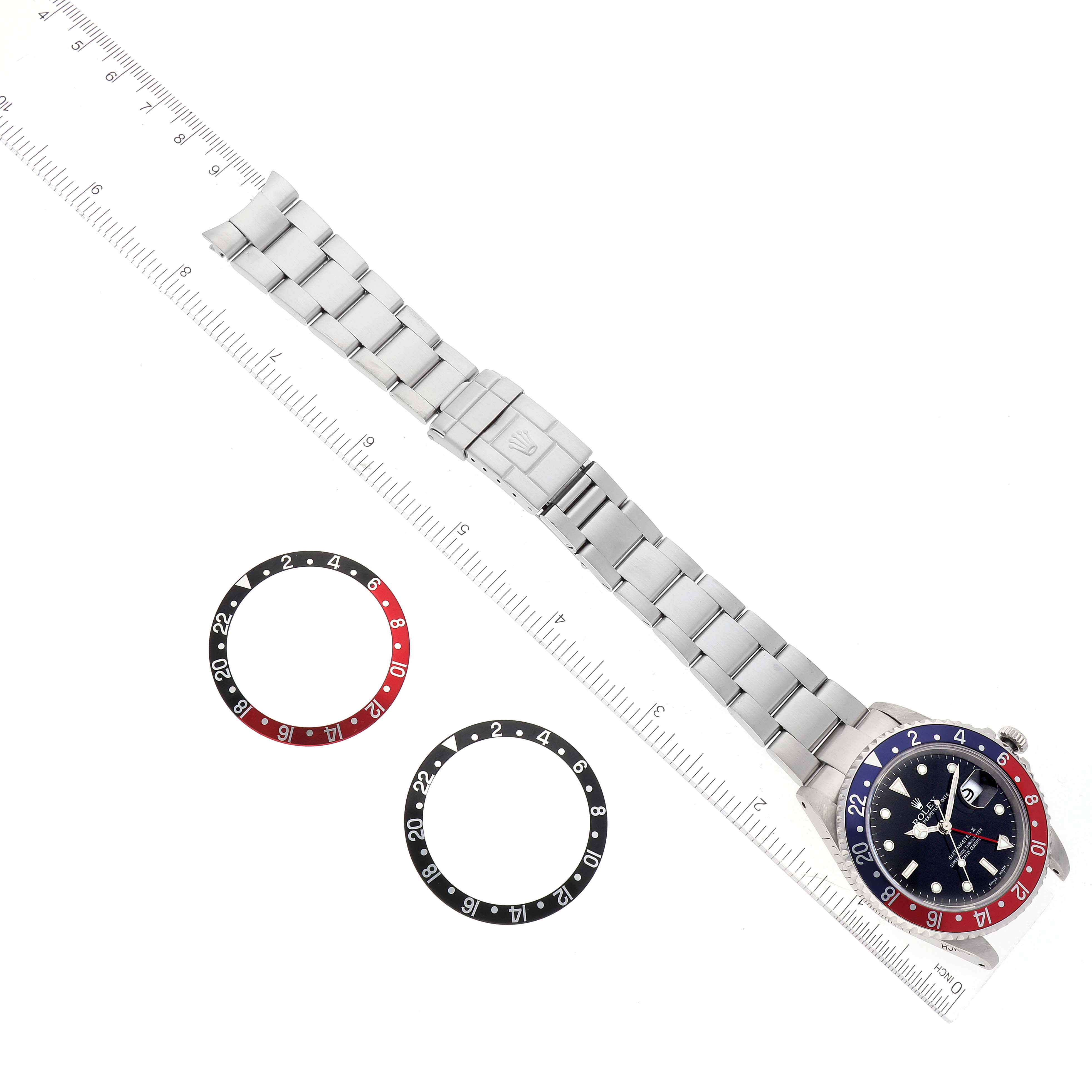 The image shows a top-down view of a Rolex GMT-Master 16710 Men
s Stainless Steel Black Dial 16710 Men
s Stainless Steel Black Dial watch with two replacement bezels and a metal bracelet.