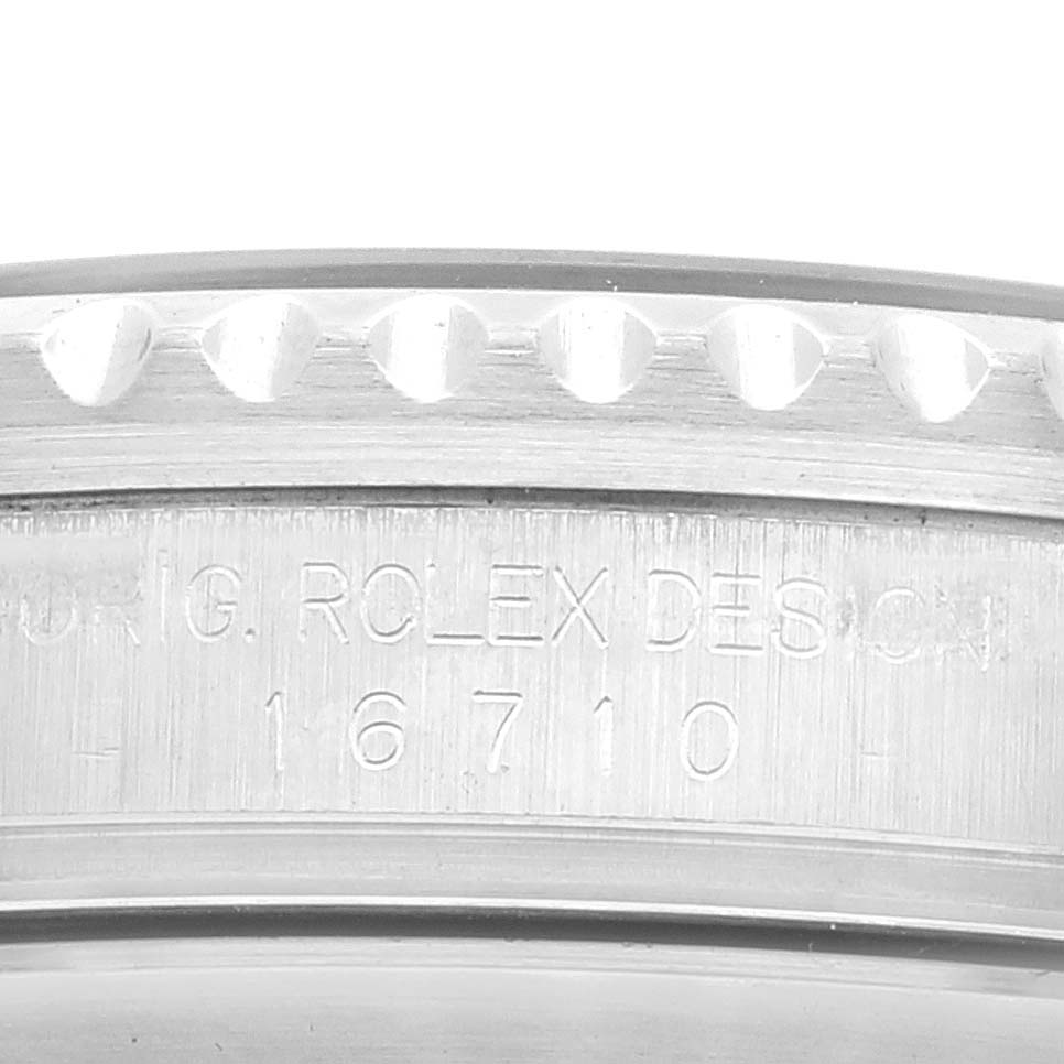 This image shows a close-up of the side of a Rolex GMT-Master 16710 Men
s Stainless Steel Black Dial 16710 Men
s Stainless Steel Black Dial watch, displaying its engraved serial number and part of the bezel.