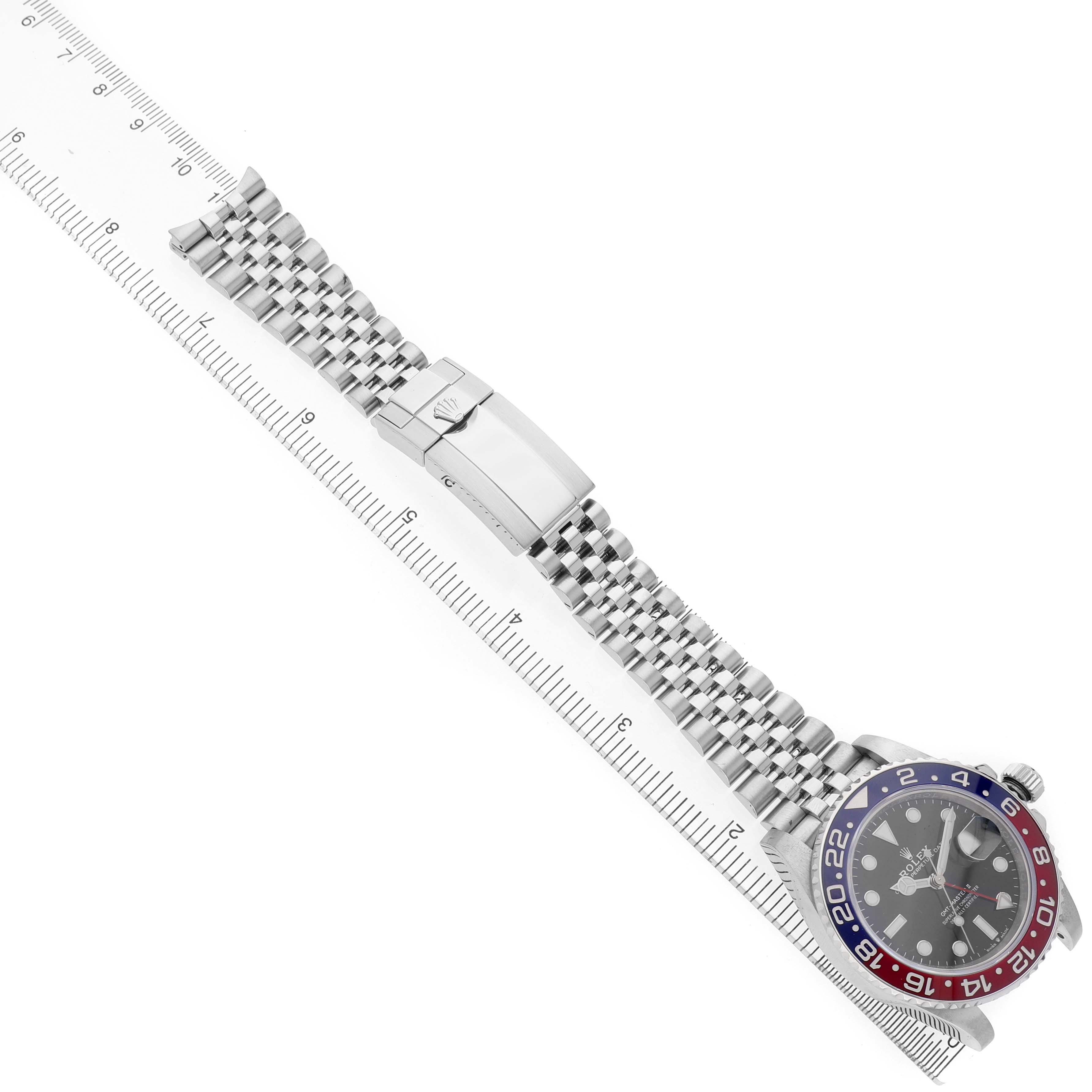 The Rolex GMT-Master 126710BLRO Men's Stainless Steel Black Dial watch is shown diagonally, displaying the bezel, dial, bracelet, and clasp alongside a ruler.