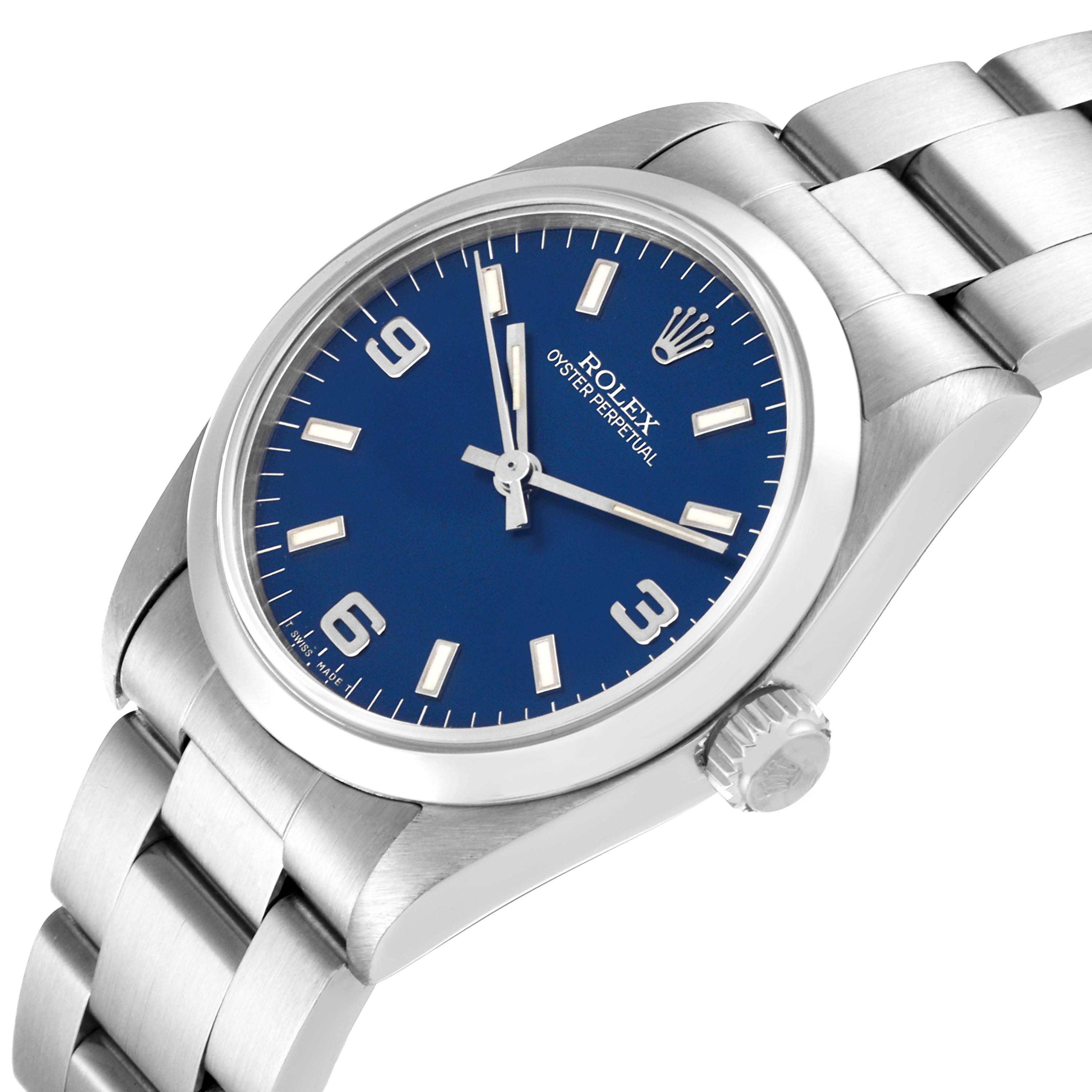 The image shows a Rolex Mid-Size 67480 Women
s Stainless Steel Blue Dial 67480 Women
s Stainless Steel Blue Dial Oyster Perpetual watch at a slight angle, highlighting the watch face, crown, and part of the bracelet.