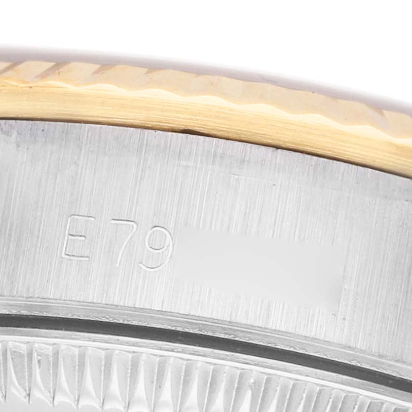 The image shows a close-up of the side and edge of the bezel of a Rolex Oyster Perpetual 67193 Women's Stainless Steel White Dial watch, featuring engraved markings.