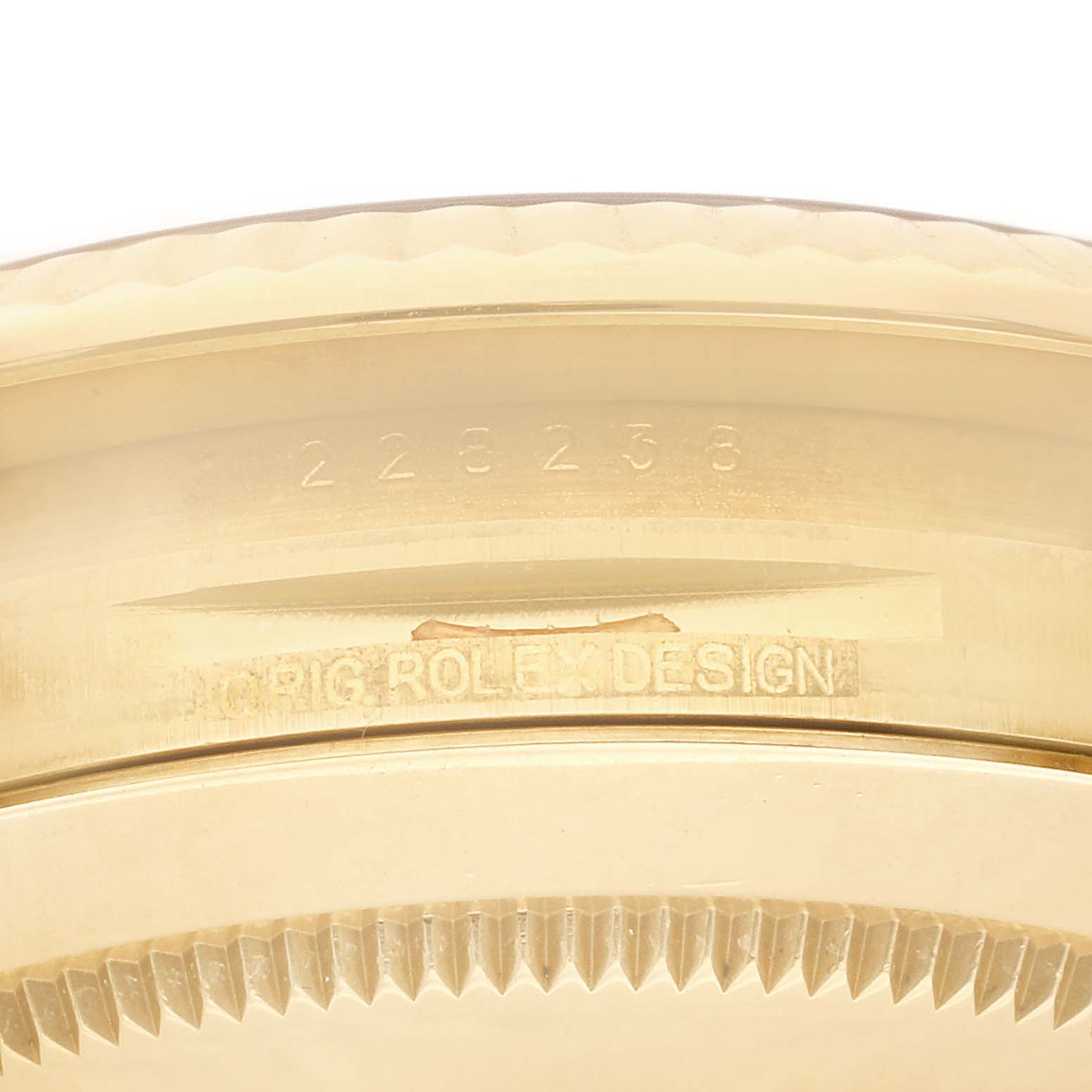 This close-up image shows the serial number and engraving on the case back edge of a Rolex President 228238 Men's Yellow Gold Black Dial 228238 Men's Yellow Gold Black Dial model watch.
