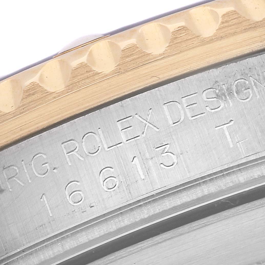 The image shows a close-up of the bezel and engraved text on the side of a Rolex Submariner 16613 Men's Steel and Gold (two tone) Blue Dial 16613 Men's Steel and Gold (two tone) Blue Dial watch.