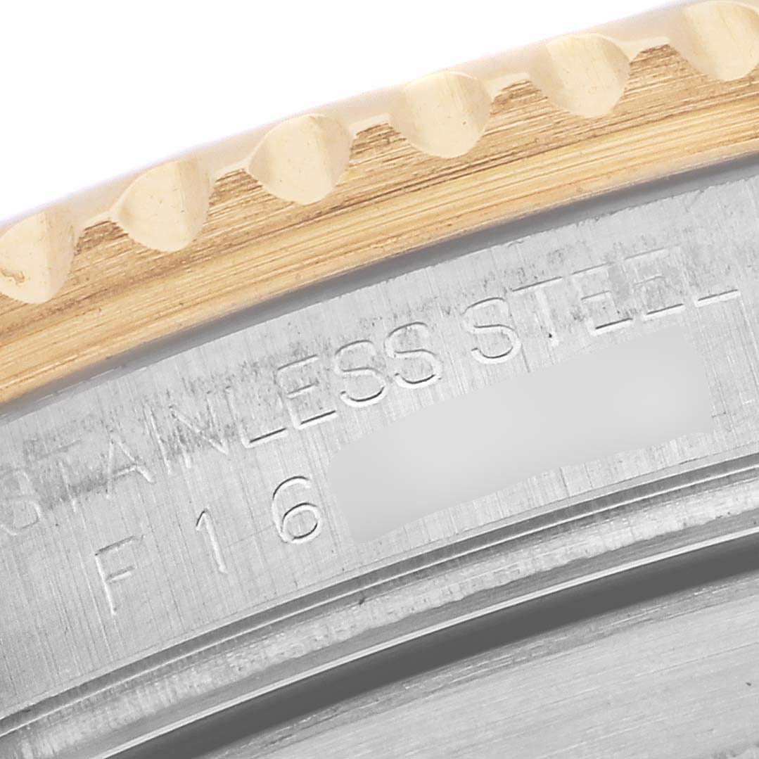 This close-up image of a Rolex Submariner 16613 Men's Steel and Gold (two tone) Blue Dial 16613 Men's Steel and Gold (two tone) Blue Dial watch focuses on the bezel and a portion of the case with engraving.