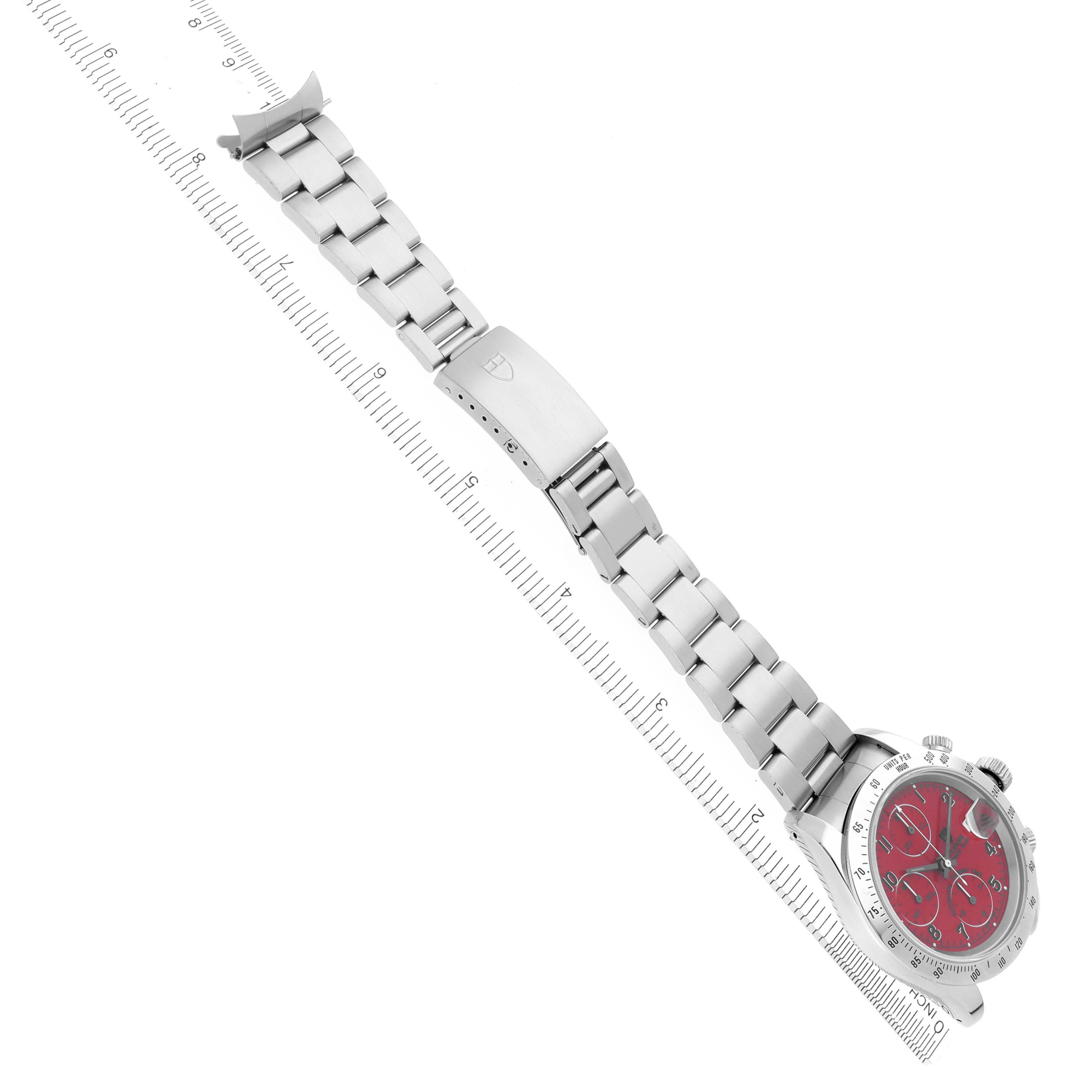 The Tudor Tiger 79280 Men's Stainless Steel Red Dial 79280 Men's Stainless Steel Red Dial watch is shown at a diagonal angle, displaying its red dial and full stainless steel bracelet alongside a ruler.