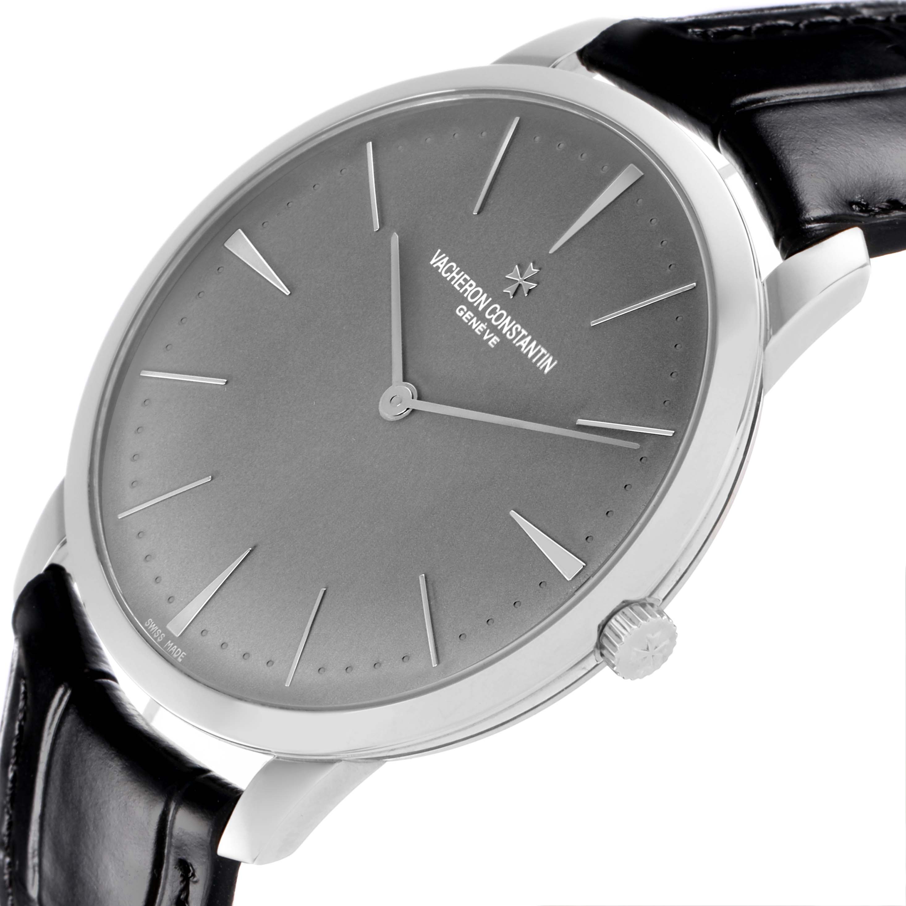 The Patrimony watch by Vacheron Constantin is shown at an angled side view, highlighting the dial, crown, and leather strap attachment.