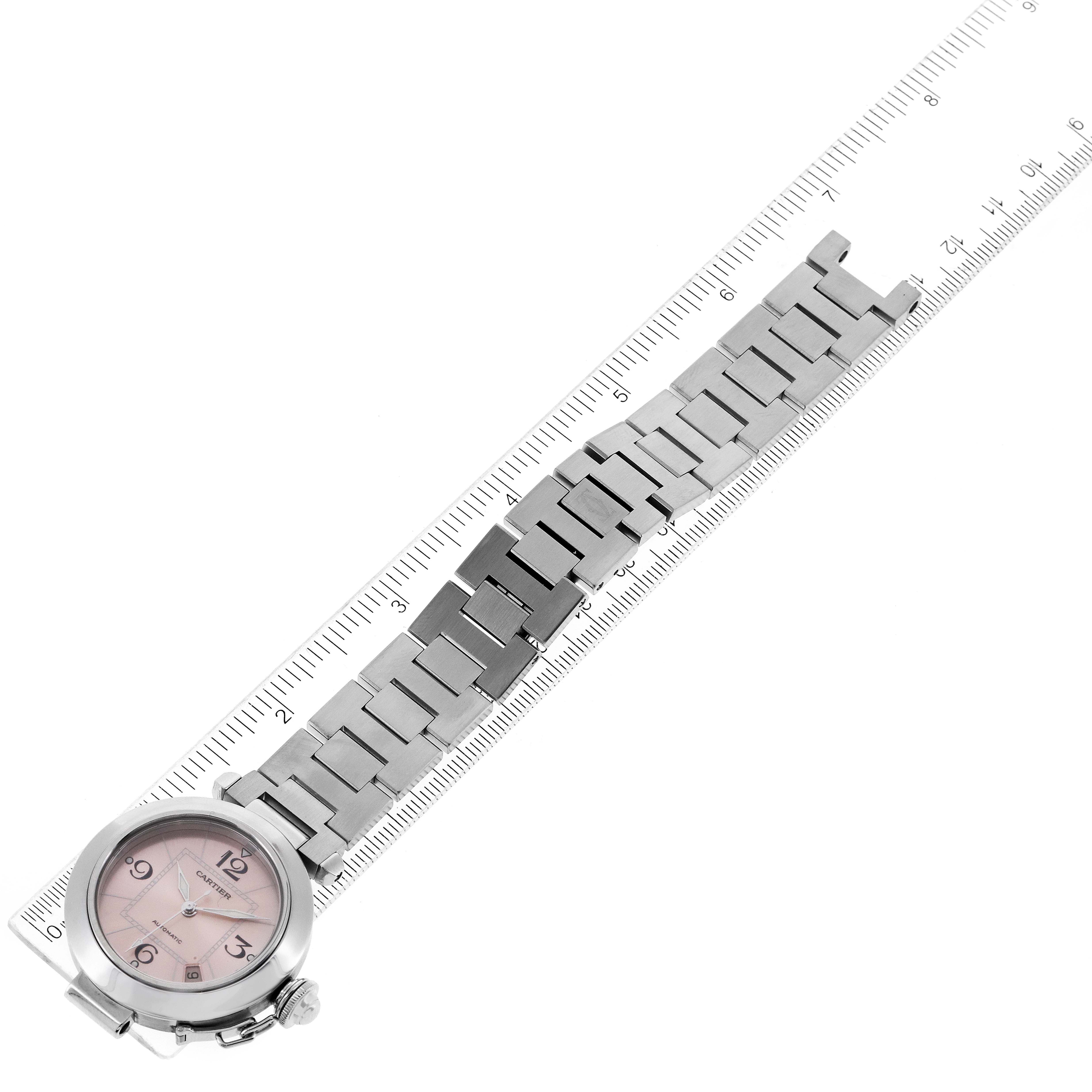 The image shows a top-down view of a Cartier Pasha W31075M7 Women's Stainless Steel Pink Dial W31075M7 Women's Stainless Steel Pink Dial model watch with its metal bracelet placed alongside a ruler.