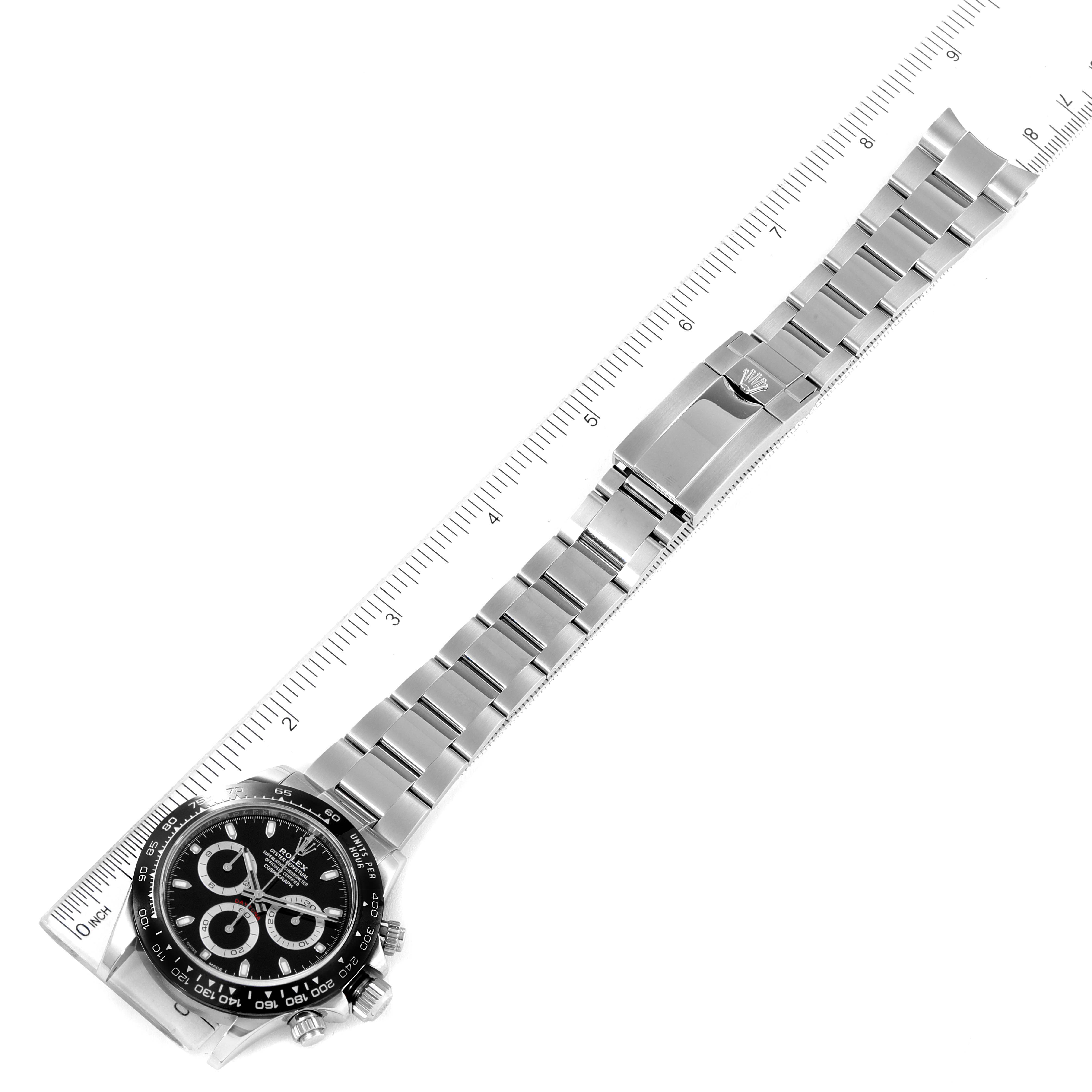 The image shows a top view of the Rolex Daytona 116500 Men
s Stainless Steel Black Dial 116500 Men
s Stainless Steel Black Dial watch, displaying its face, bezel, and full bracelet against a ruler scale.