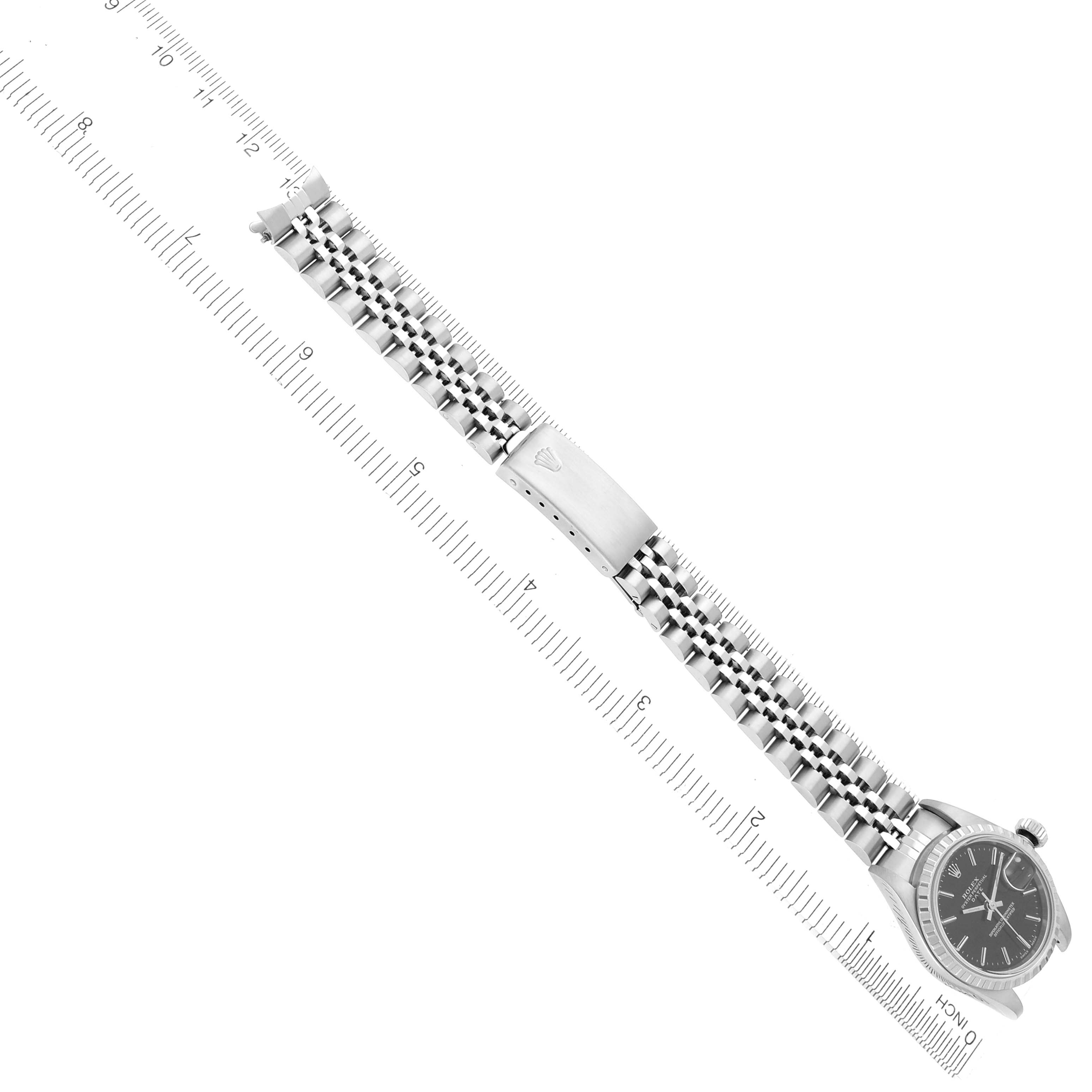 The Rolex Date 79240 Women's Stainless Steel Black Dial 79240 Women's Stainless Steel Black Dial watch is shown from the top angle, displaying the face, bracelet, and clasp next to a ruler.