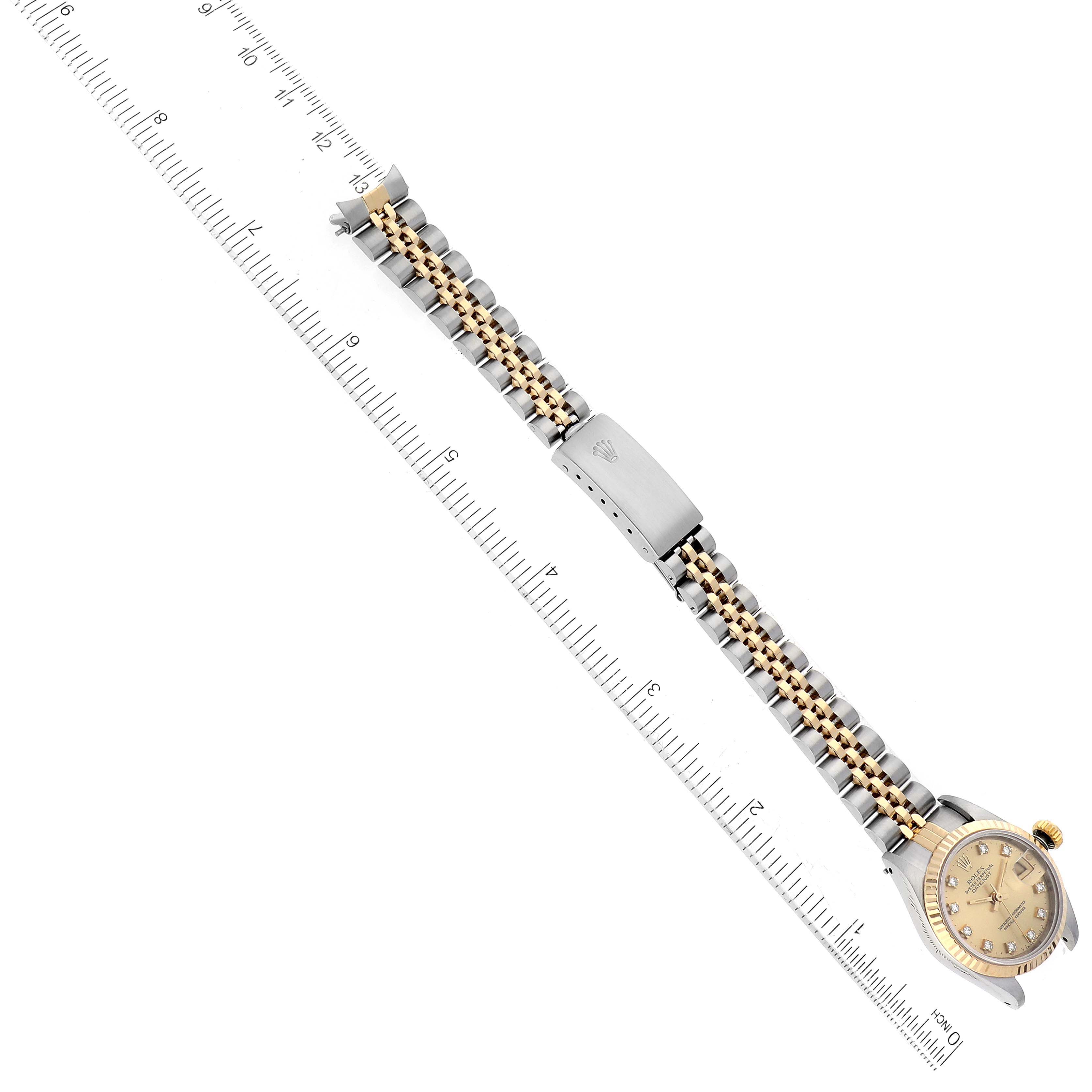 The image shows a top-down view of a Rolex Datejust 69173 Women's Steel and Gold (two tone) Champagne Dial 69173 Women's Steel and Gold (two tone) Champagne Dial watch, including the face, band, and clasp, alongside a ruler for scale.