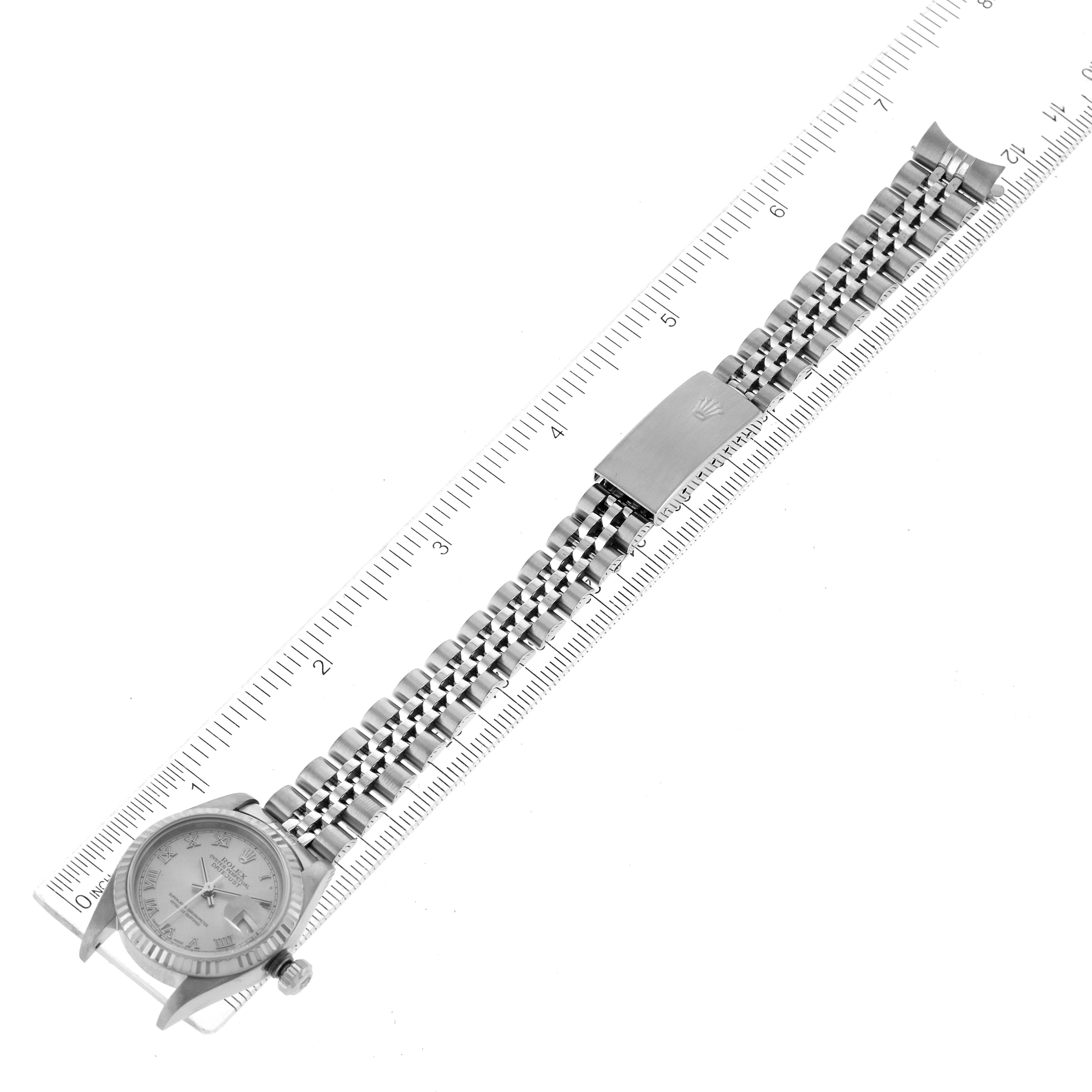 The image shows a Rolex Datejust 79174 Women
s Stainless Steel Silver Dial 79174 Women
s Stainless Steel Silver Dial watch laid flat on a ruler, highlighting the band and clasp.