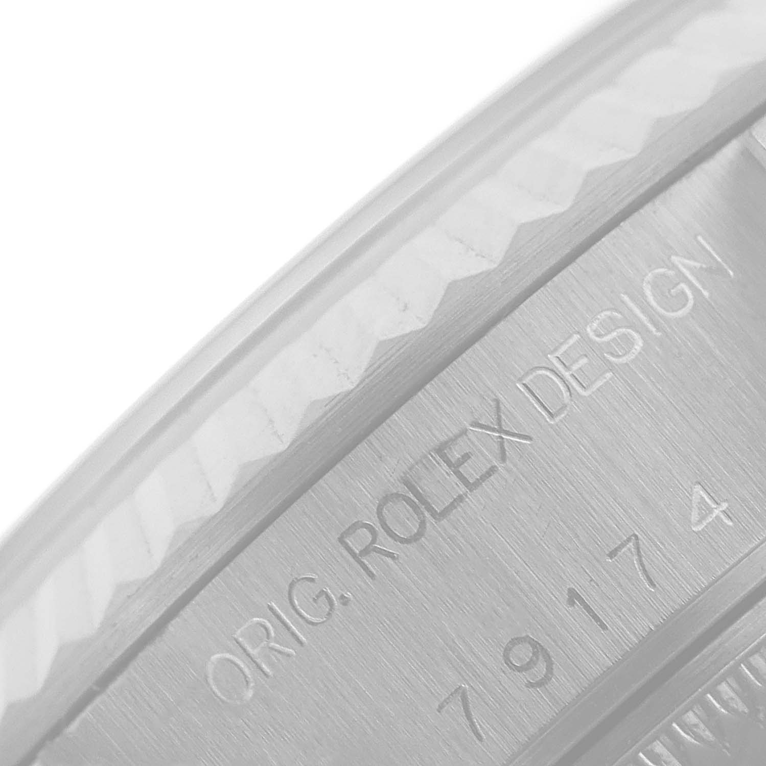 This is a close-up image of the case side and bezel of a Rolex Datejust 79174 Women
s Stainless Steel Silver Dial 79174 Women
s Stainless Steel Silver Dial, showing the engraving "ORIG. ROLEX DESIGN" with its reference number.