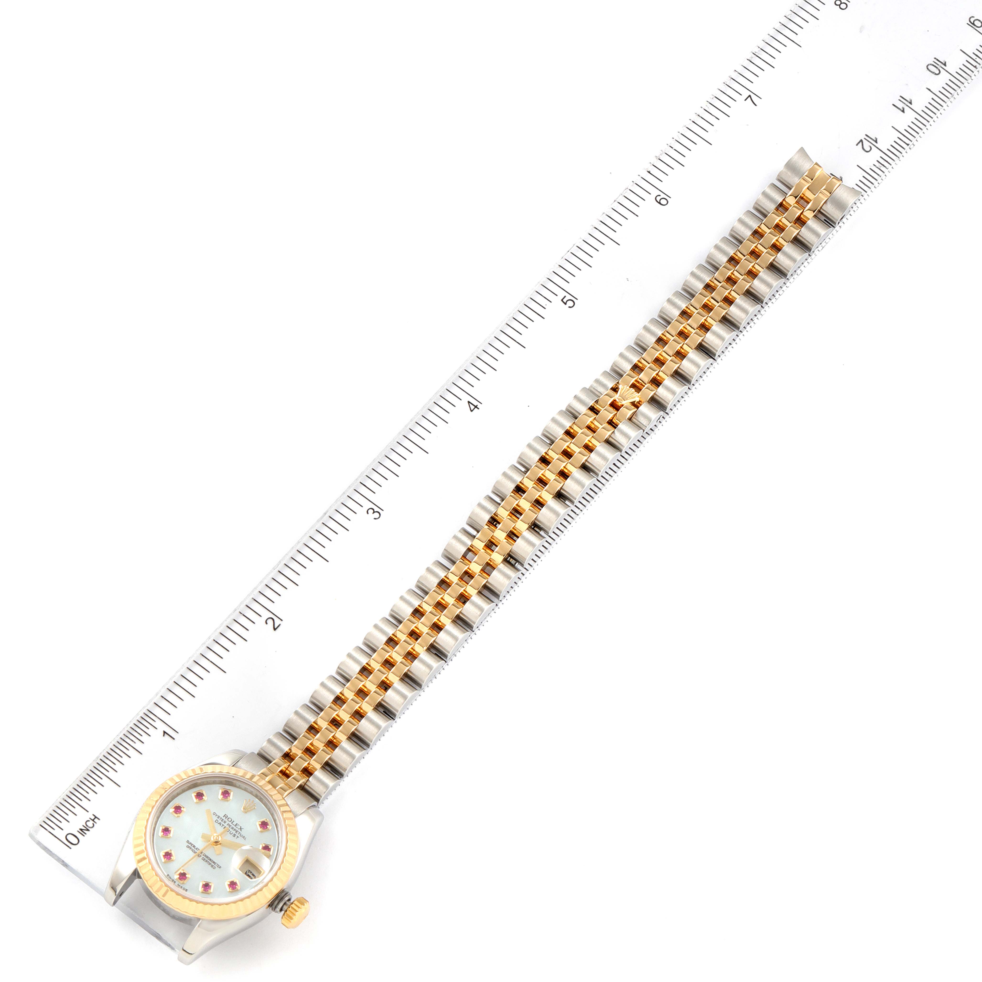 The image shows a full frontal view of a Rolex Datejust 179173 Women's Steel and Gold (two tone) Mother of Pearl Dial 179173 Women's Steel and Gold (two tone) Mother of Pearl Dial watch, including its face and entire bracelet, alongside a ruler for scale.