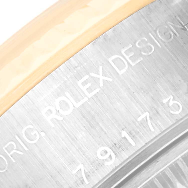 The image shows a close-up of the engraved text and serial number on the side of the Rolex Datejust 79173 Women's Steel and Gold (two tone) Champagne Dial 79173 Women's Steel and Gold (two tone) Champagne Dial watch case.