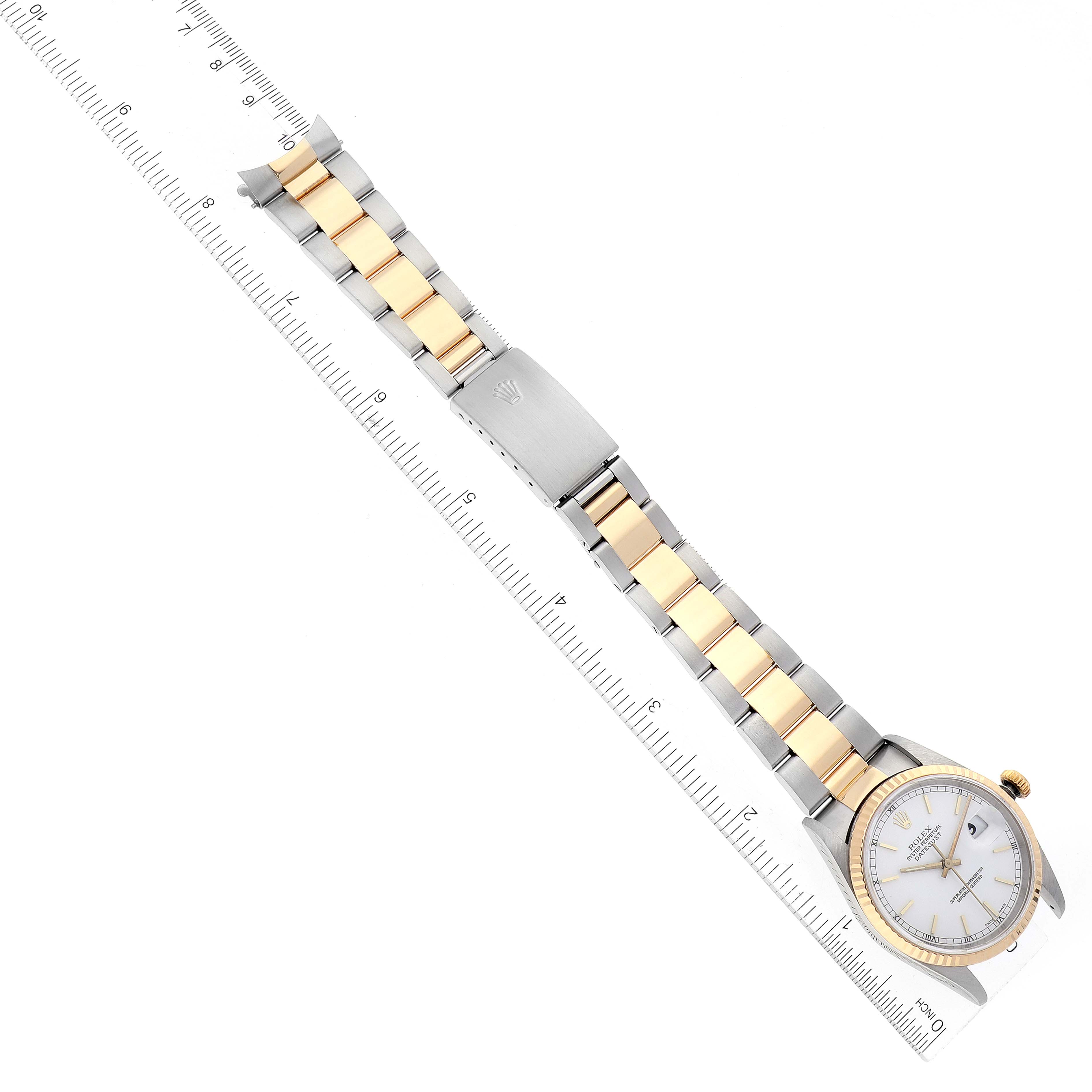 The image shows an overhead view of a Rolex Datejust 16233 Men's Steel and Gold (two tone) White Dial 16233 Men's Steel and Gold (two tone) White Dial watch, displaying its two-tone bracelet, clasp, and face next to a ruler.