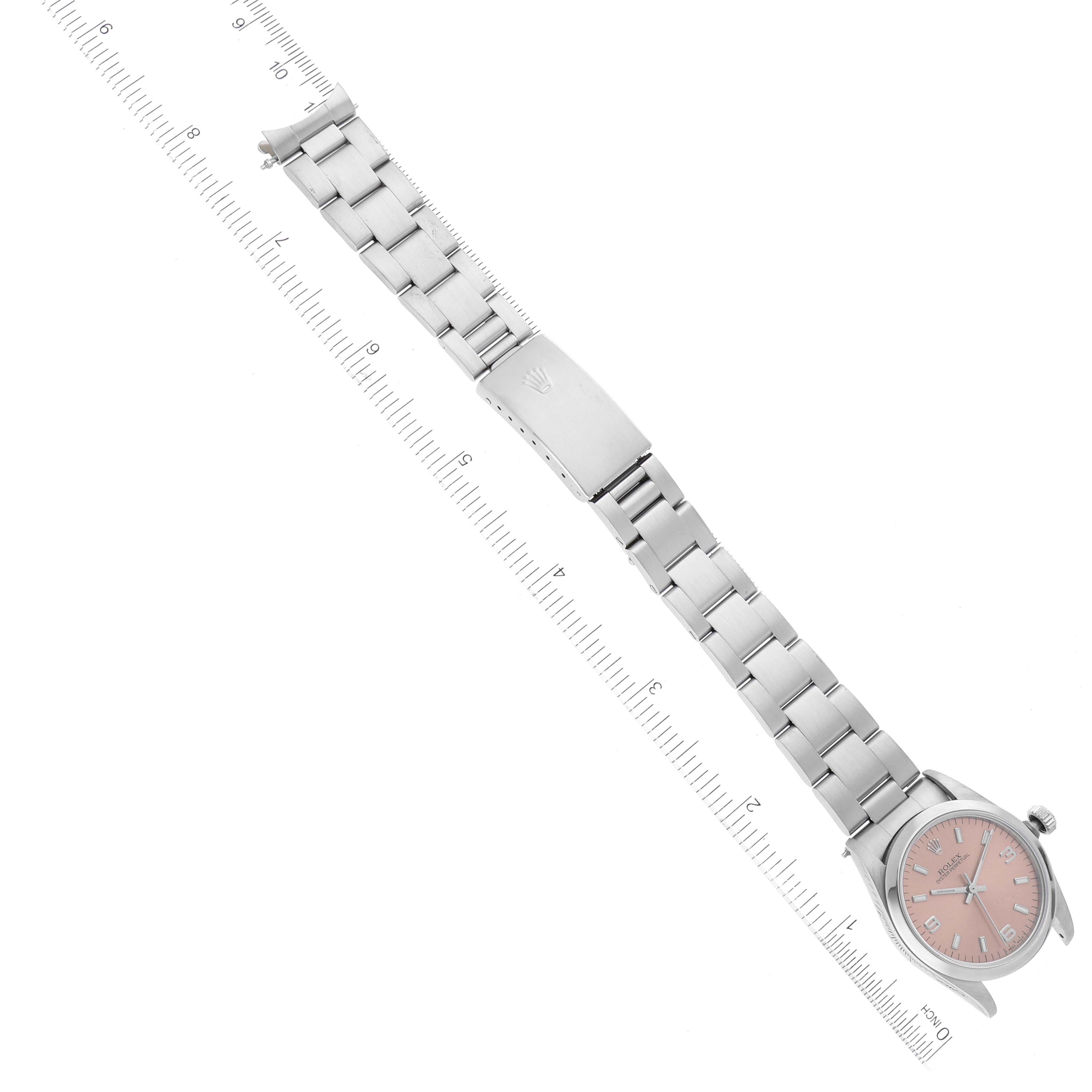 This image shows a Rolex Mid-Size 67480 Women
s Stainless Steel Pink Dial 67480 Women
s Stainless Steel Pink Dial model watch laid flat, displaying the bracelet, clasp, and face, with rulers for scale.