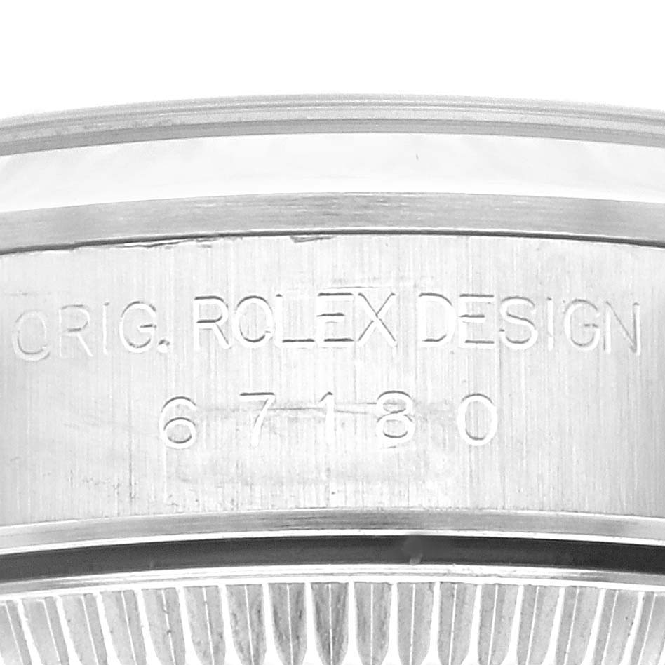 The image shows the engraved side of the bezel of a Rolex Oyster Perpetual 67180 Women's Stainless Steel Black Dial 67180 Women's Stainless Steel Black Dial, including design details and model number (67180).