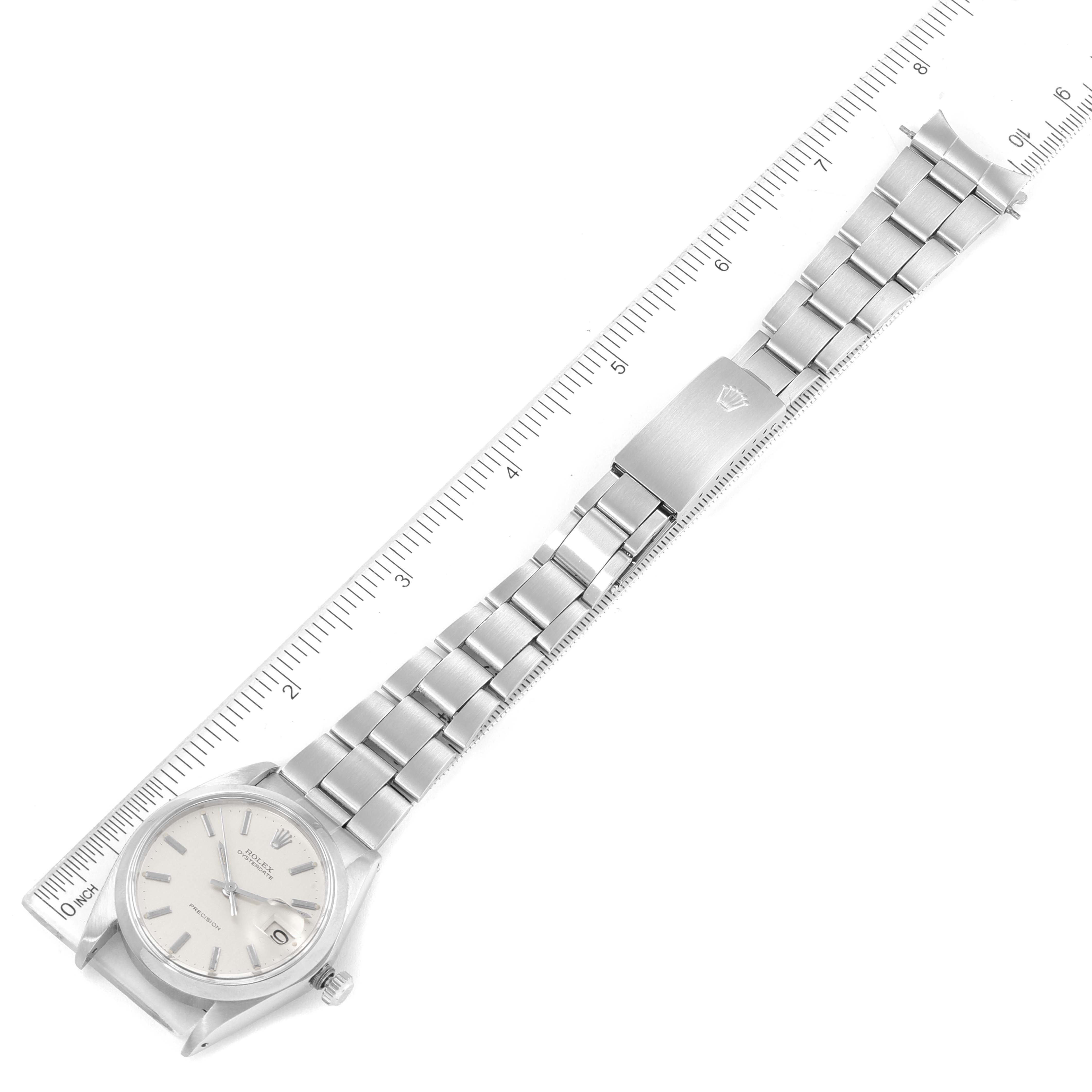 The image shows a top-down view of a Rolex Date 6694 Men's Stainless Steel Silver Dial 6694 Men's Stainless Steel Silver Dial model watch with a stainless steel bracelet next to a ruler for scale.