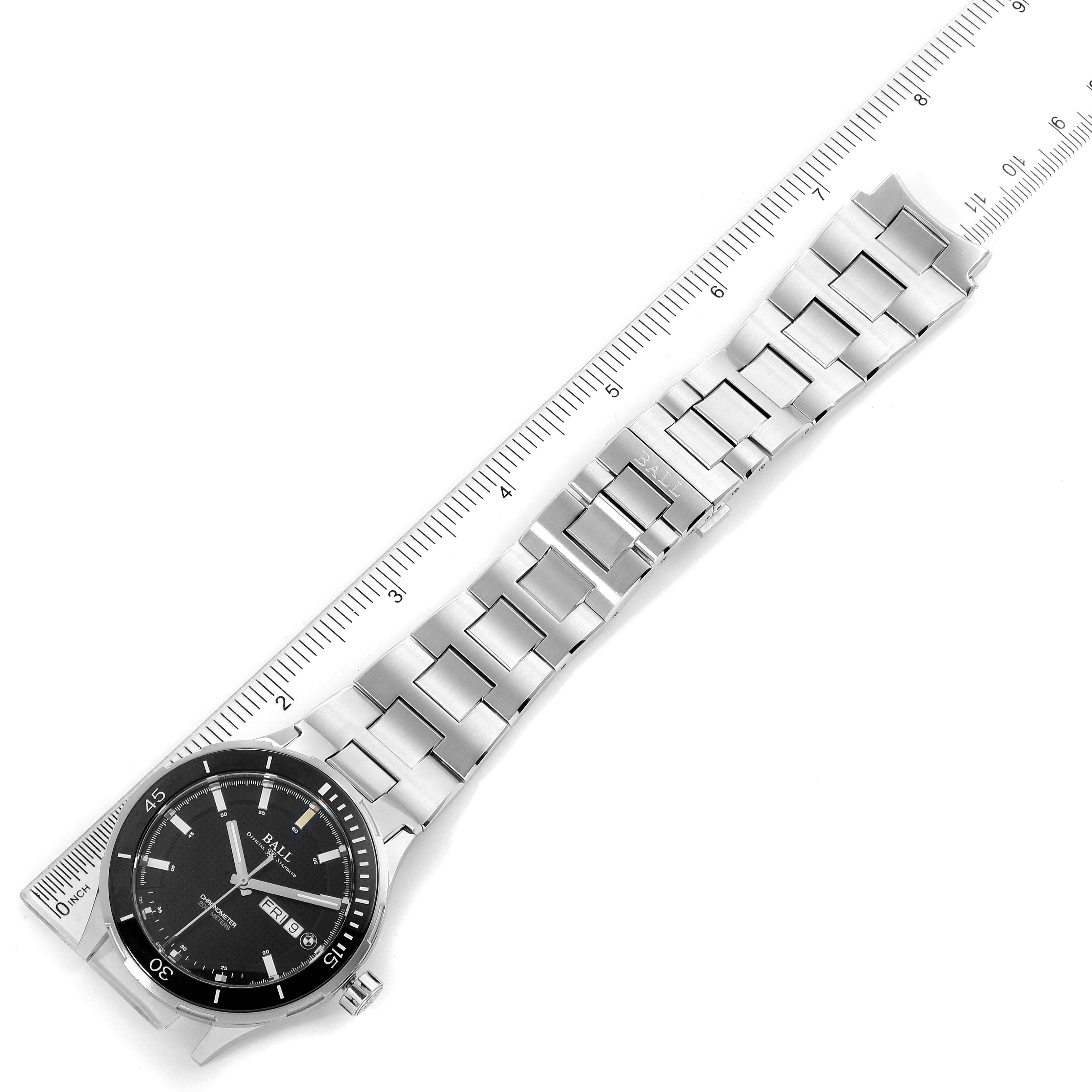 This image shows a Ball Roadmaster DM3010B-SCJ-BE Men's Stainless Steel Black Dial DM3010B-SCJ-BE Men's Stainless Steel Black Dial watch placed beside a ruler, highlighting the watch face and metal bracelet.