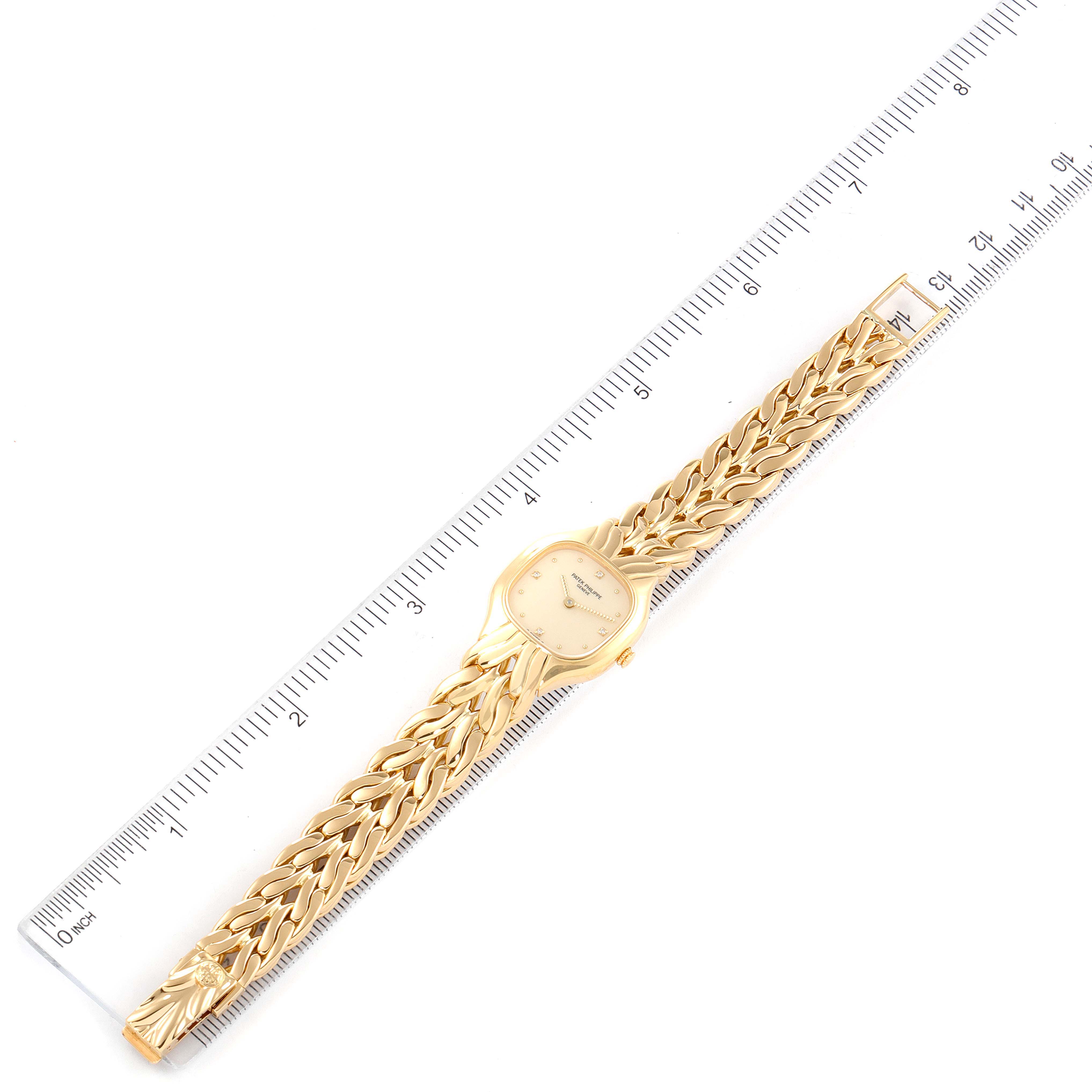 The image shows a top-down view of a Patek Philippe La Flamme  4815/1J Women's Yellow Gold Beige Dial 4815/1J Women's Yellow Gold Beige Dialwatch with a gold chain link band next to a ruler.